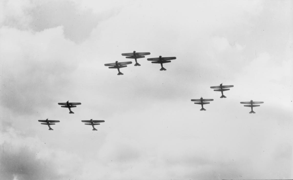 Nio stycken flygplan flyger i V-formation