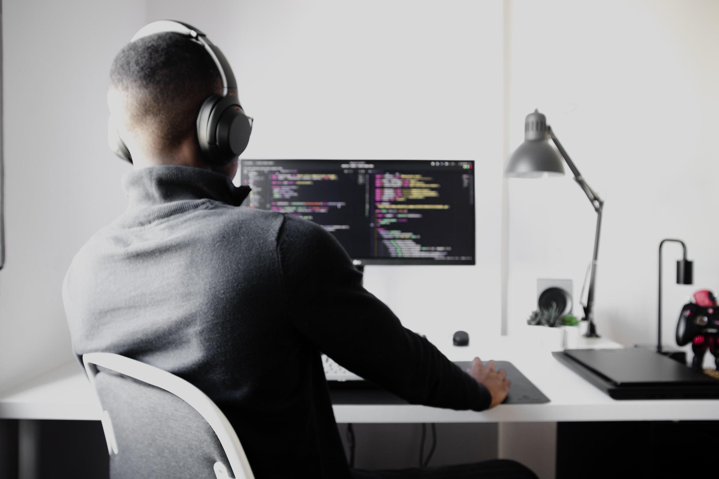 rygger på man som läser til programmerare vid skrivbord