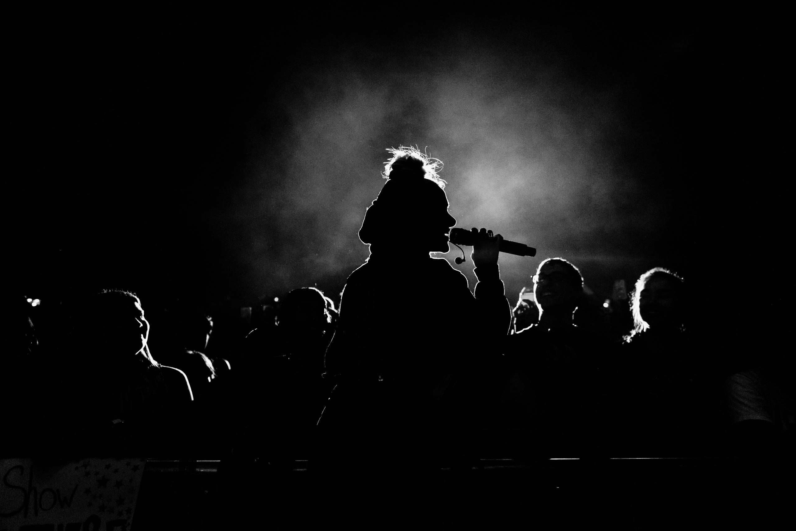 ett publikhav i motljus blickar mot en scen där en musiker står