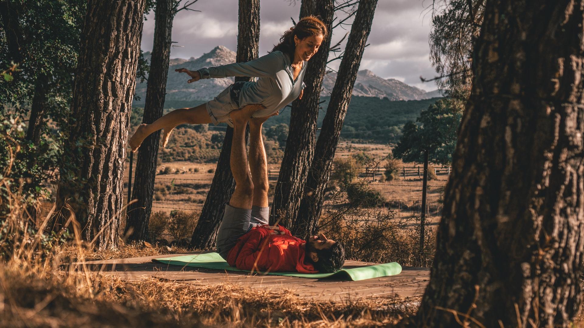 par gör acroyoga i skogen