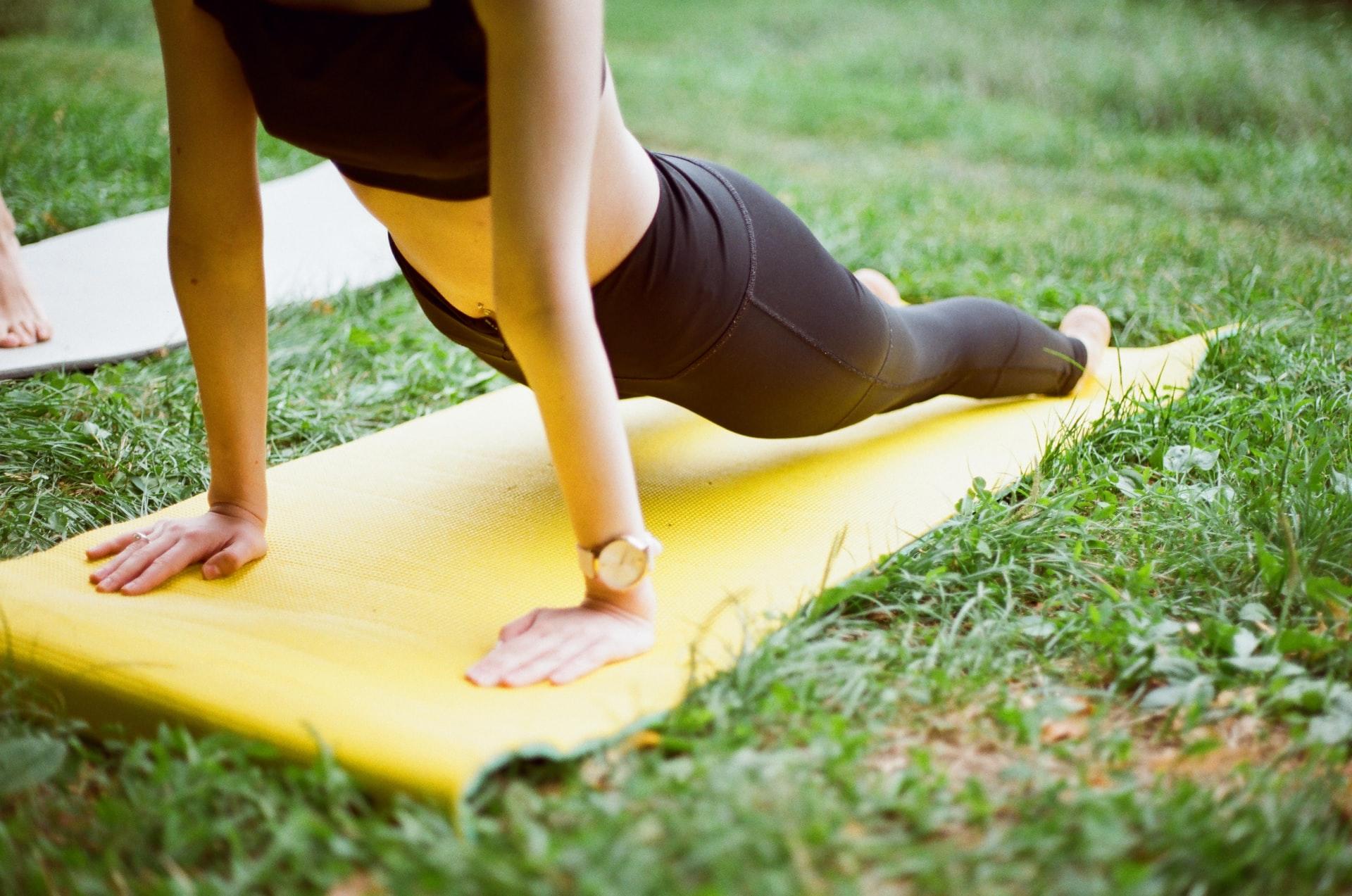 två personer gör yoga på gräsmatta