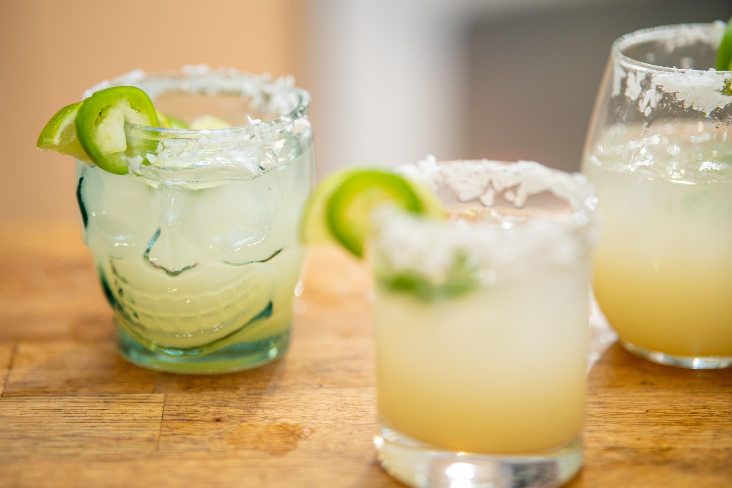 tre glas fyllda med margarita står på ett träbord