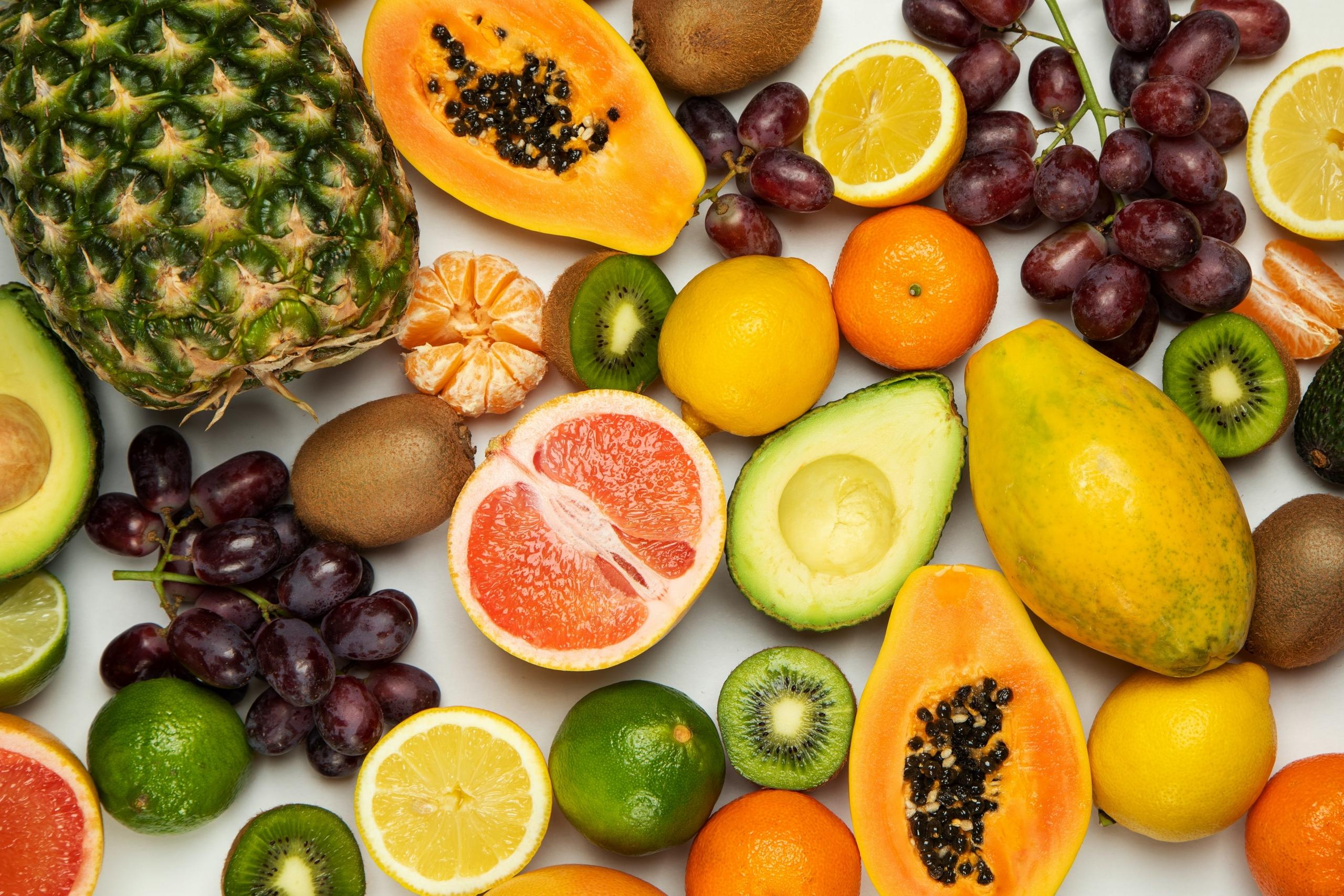 ett bord fyllt med frukter så som ananas, kiwi och apelsin