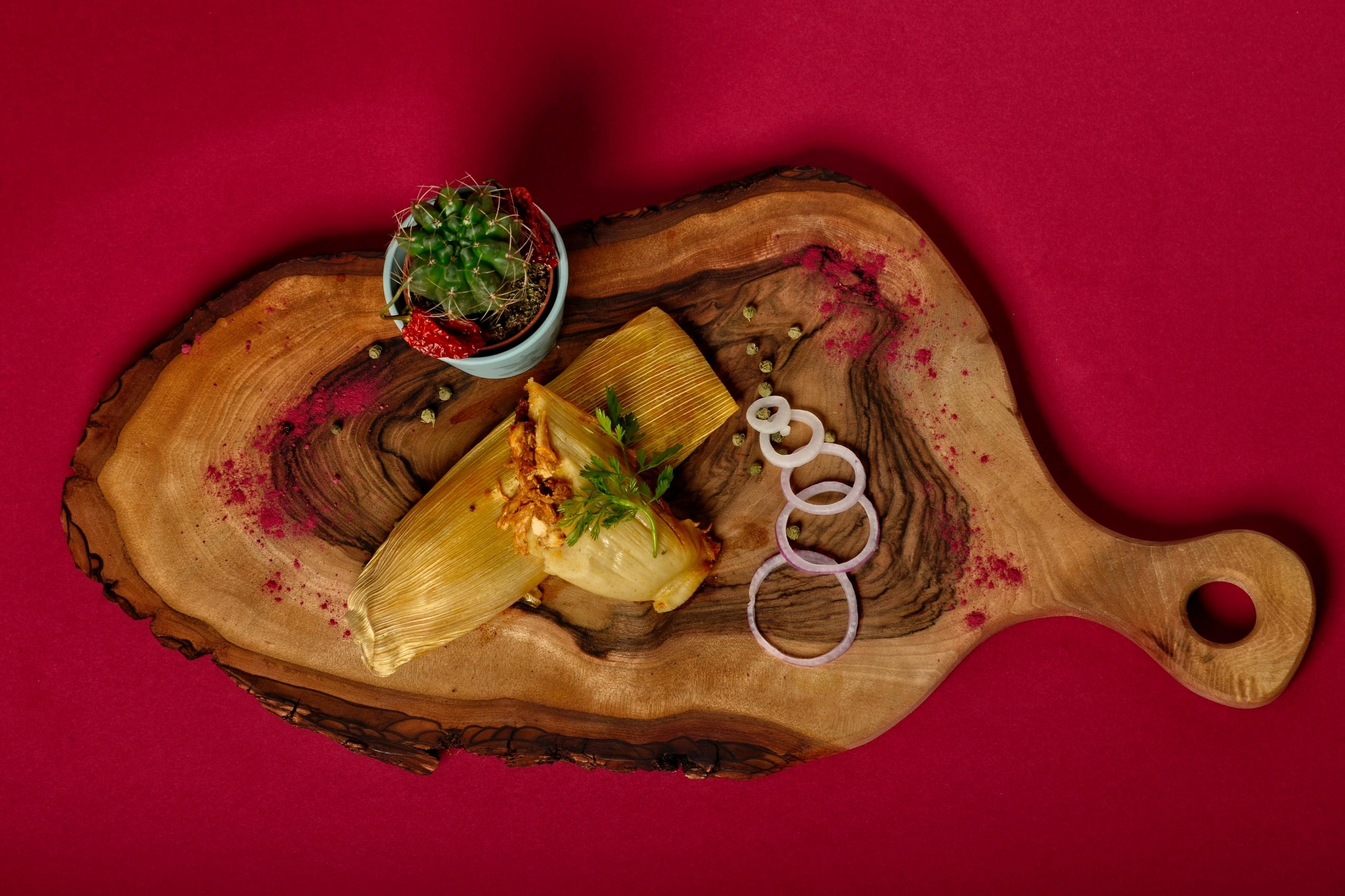 tamales på en träplanka mot en röd bakgrund