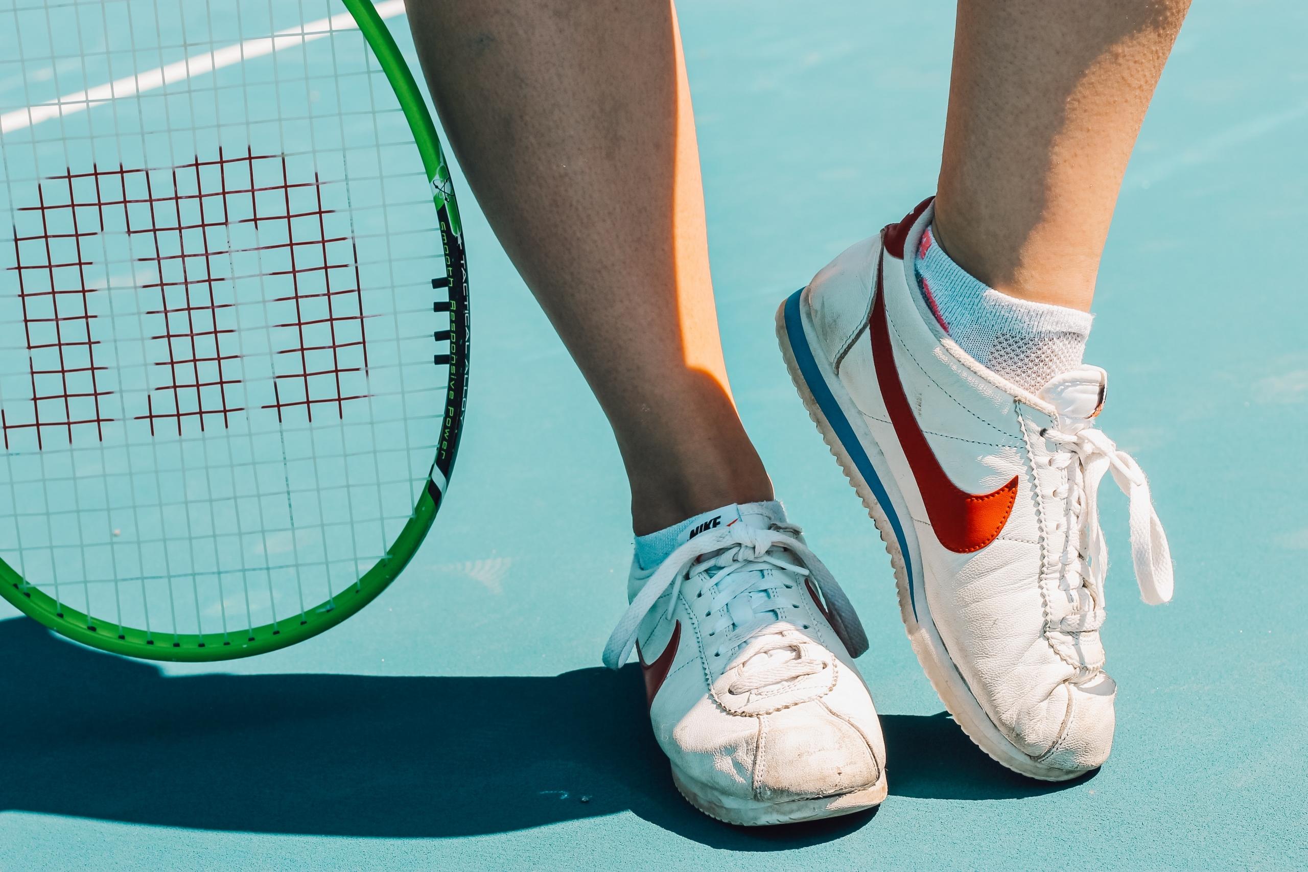En tennisspelare som står i sina tennisskor på banan.