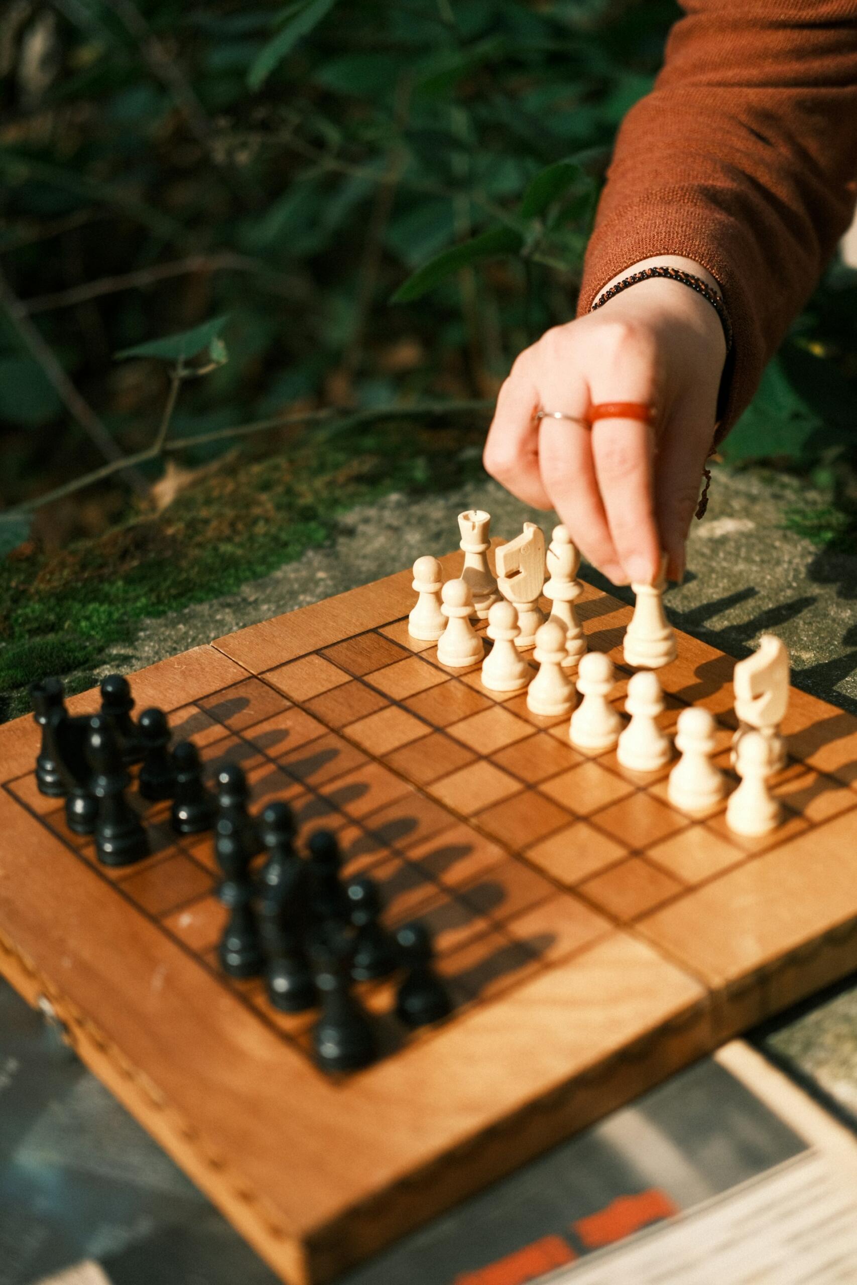 Bild på ett schackbräde och en hand som flyttar den vita kungen. Bild av Nina Zeynep Güler via Unsplash+