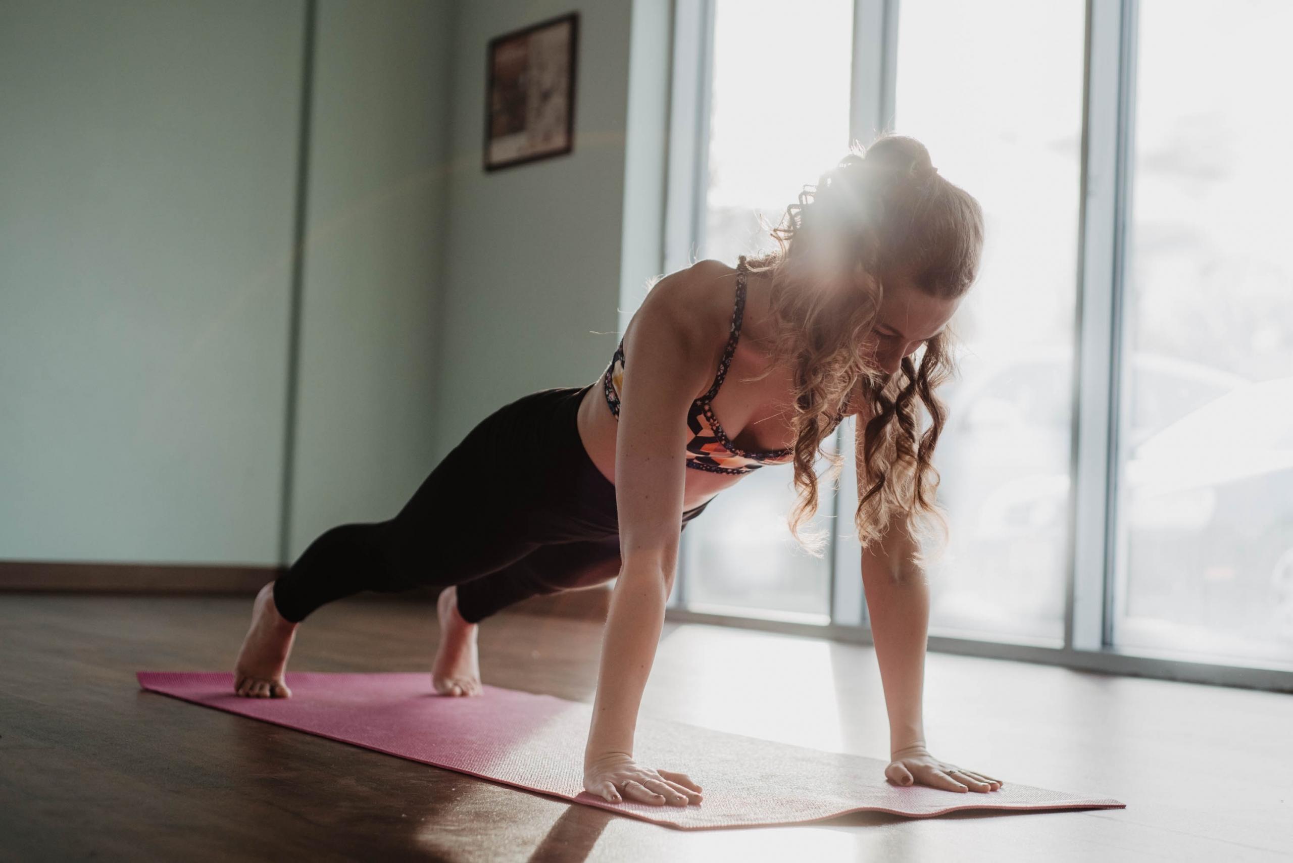 Kvinna står i yogaposition på yogamatta