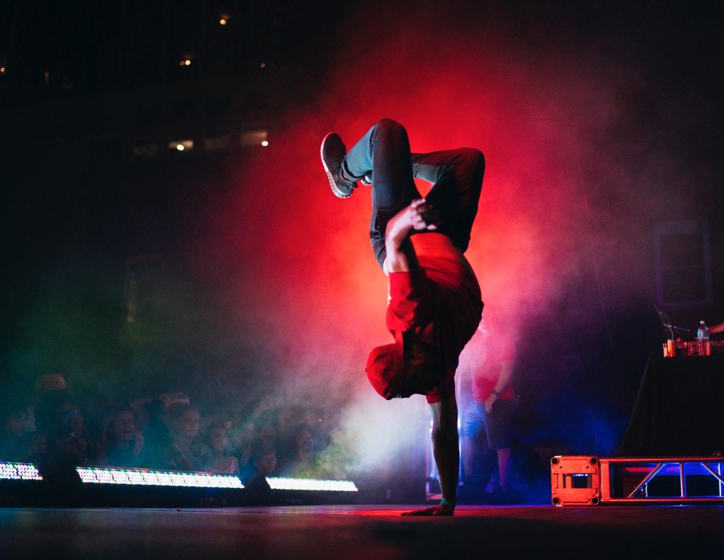 man dansar breakdance på scen med rött strålkastarljus