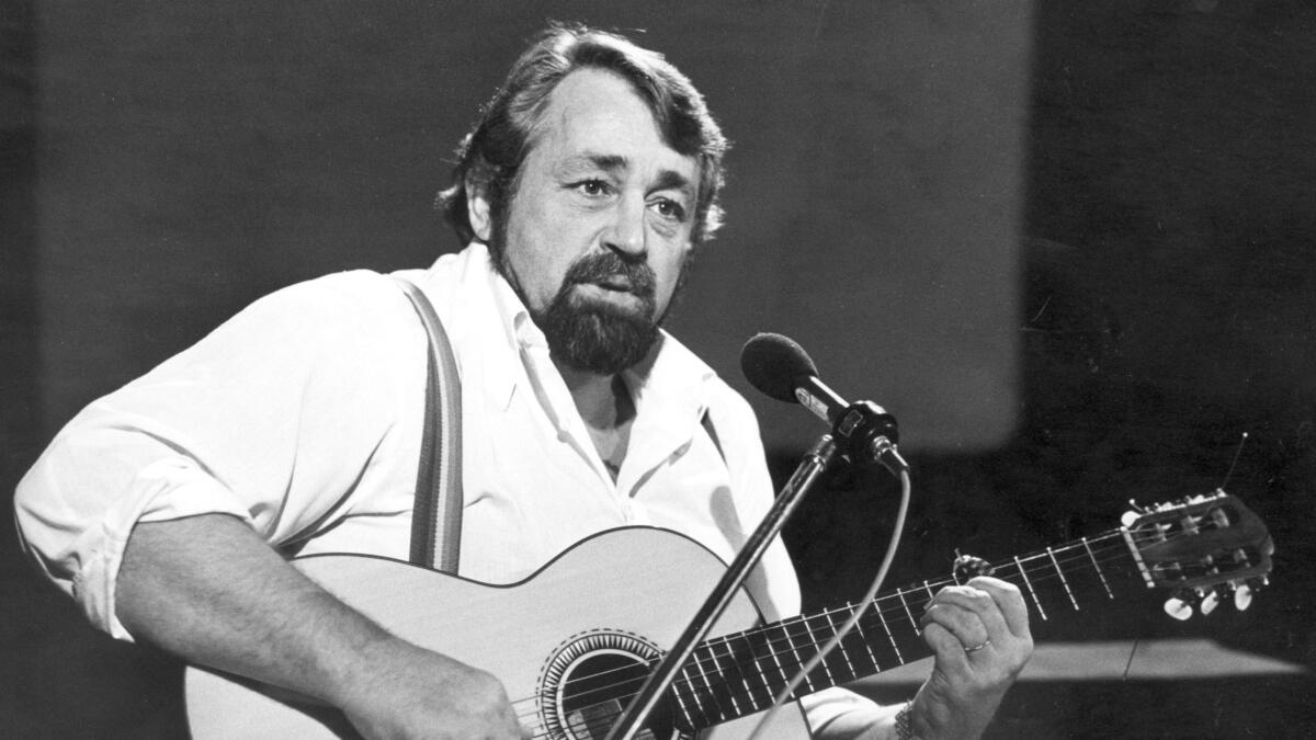 Cornelis Vreeswijk står på scen och spelar gitarr