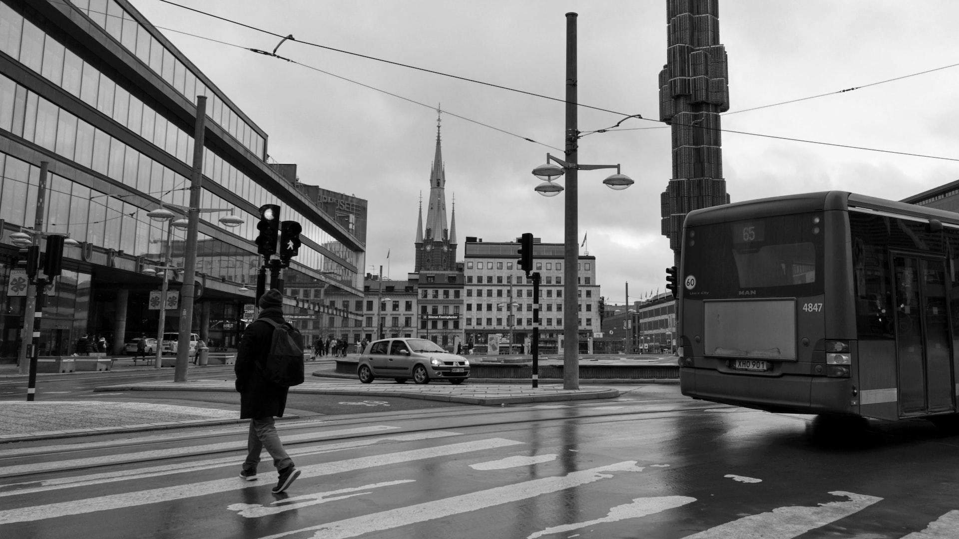En svartvit bild över Sergels Torg i Stockholm. Man ser både biltrafik och människor.