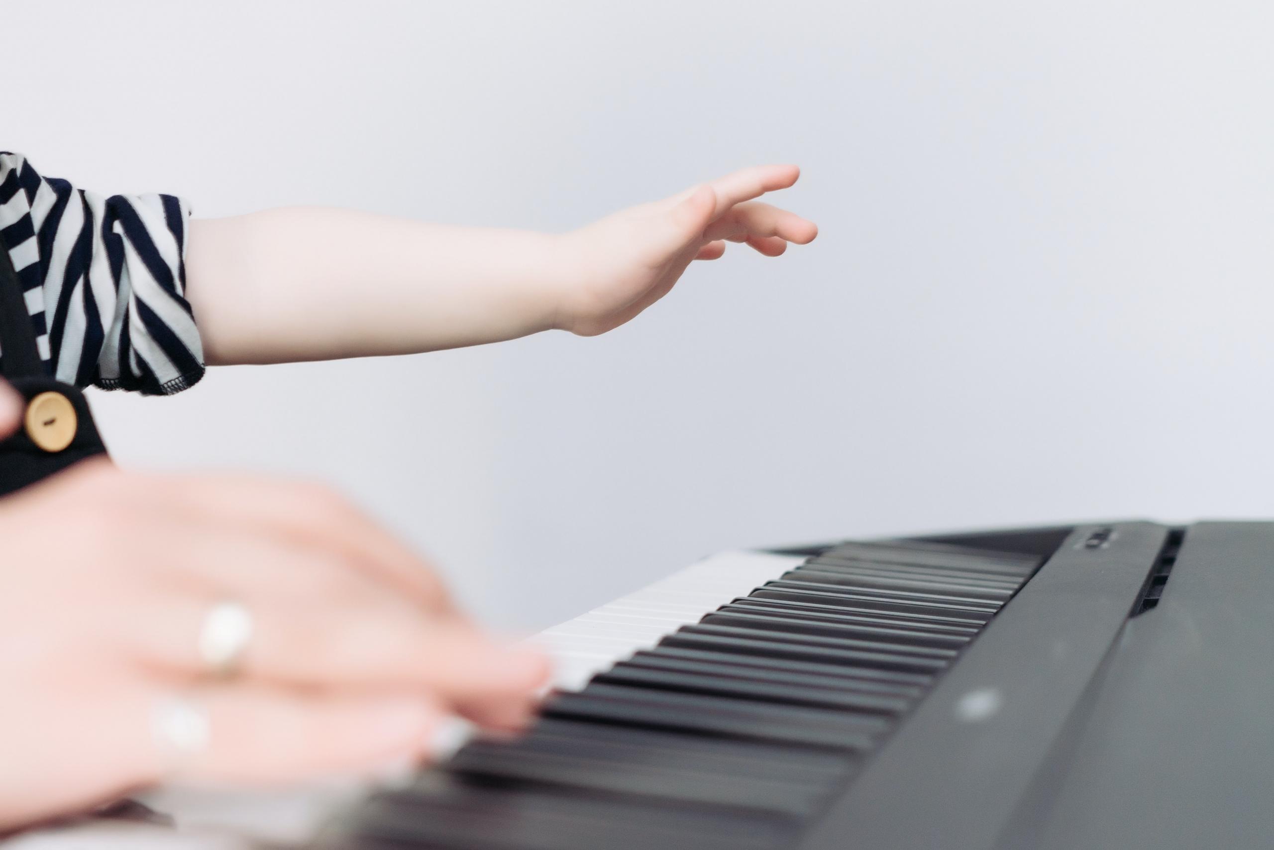 Vuxen med barn i knät som spelar el-piano