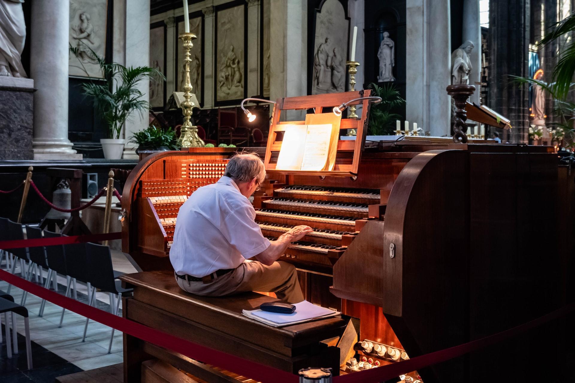 Man som sitter framför en träorgel längst bak i en stor kyrksal.
