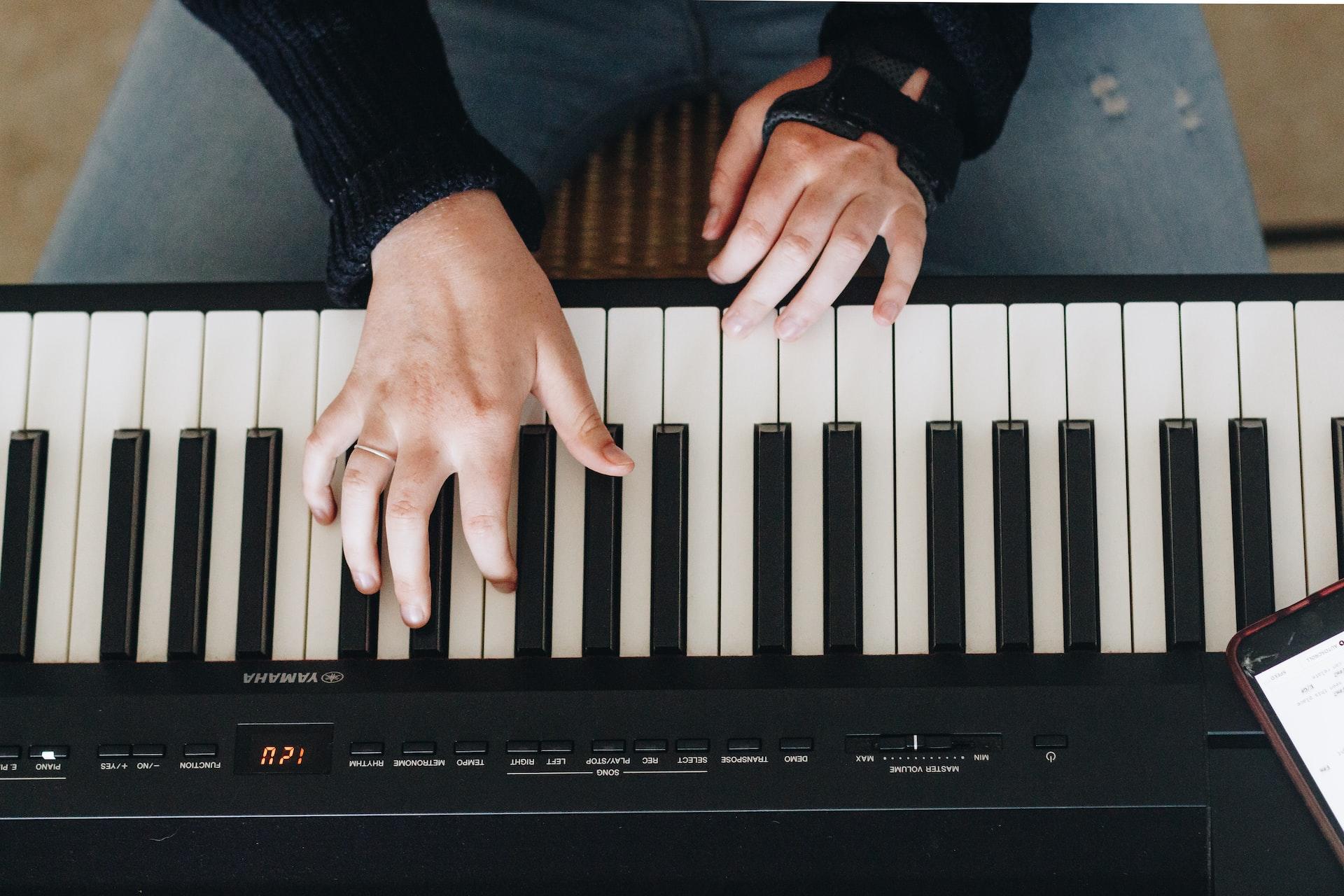 Bild tagen ovanifrån av händer som spelar på ett elektriskt piano.