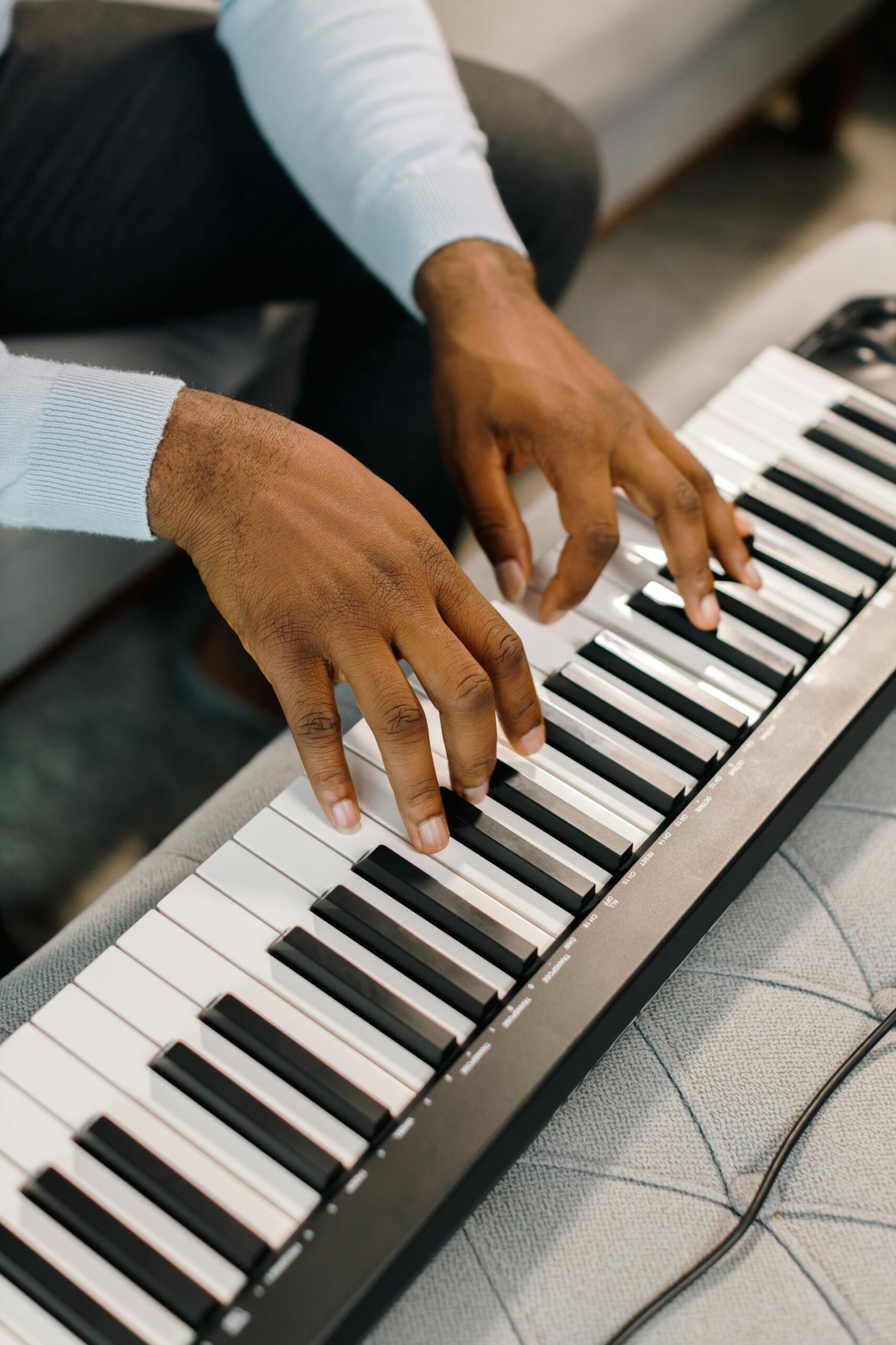 Närbild på ett par händer som spelar på ett elpiano. Bild av Ben Iwara via Unsplash+
