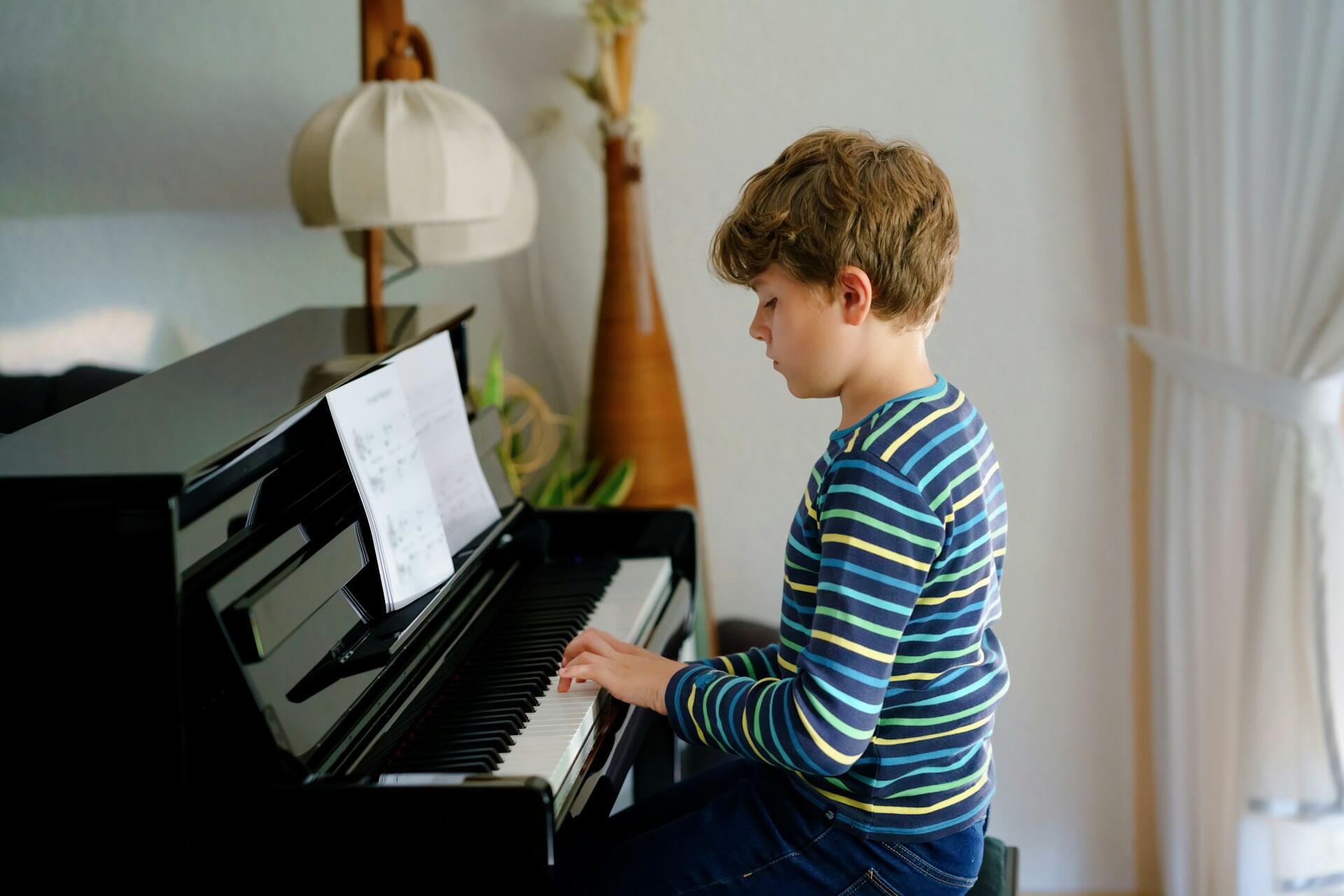 Pojke som sitter rakryggad och spelar piano.