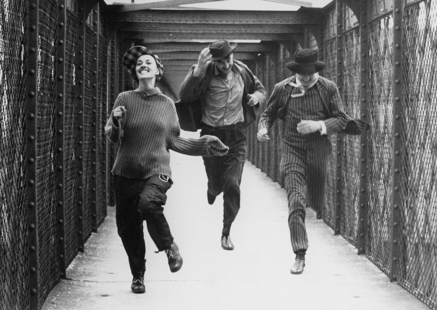 Bild ur filmen Jules et Jim från 1962. Tre personer springer på en gångbro rakt emot kameran.