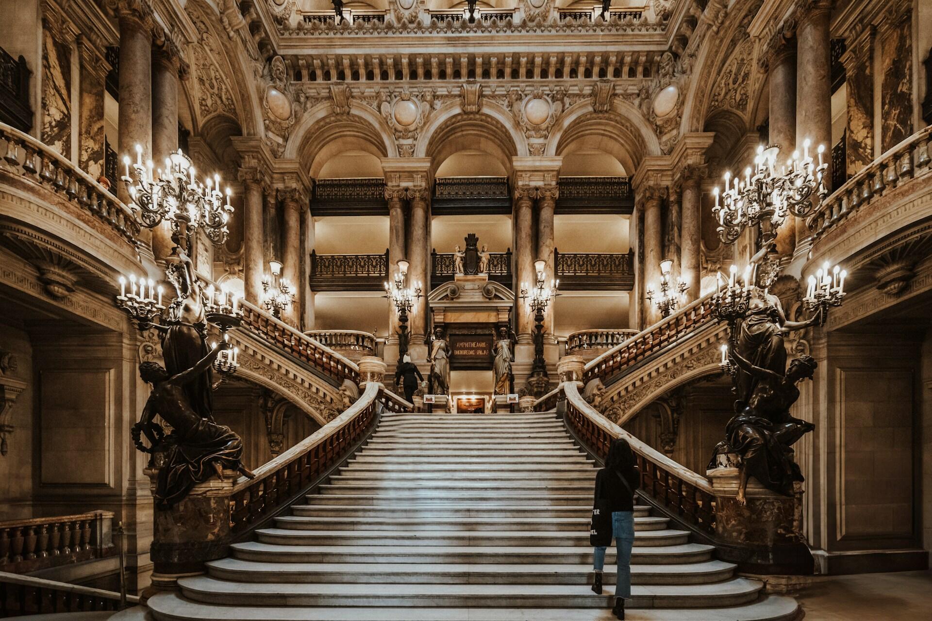 En bild på interiören på den stora operan i Paris. På bilden syns de stora väl utsmyckade trapporna.