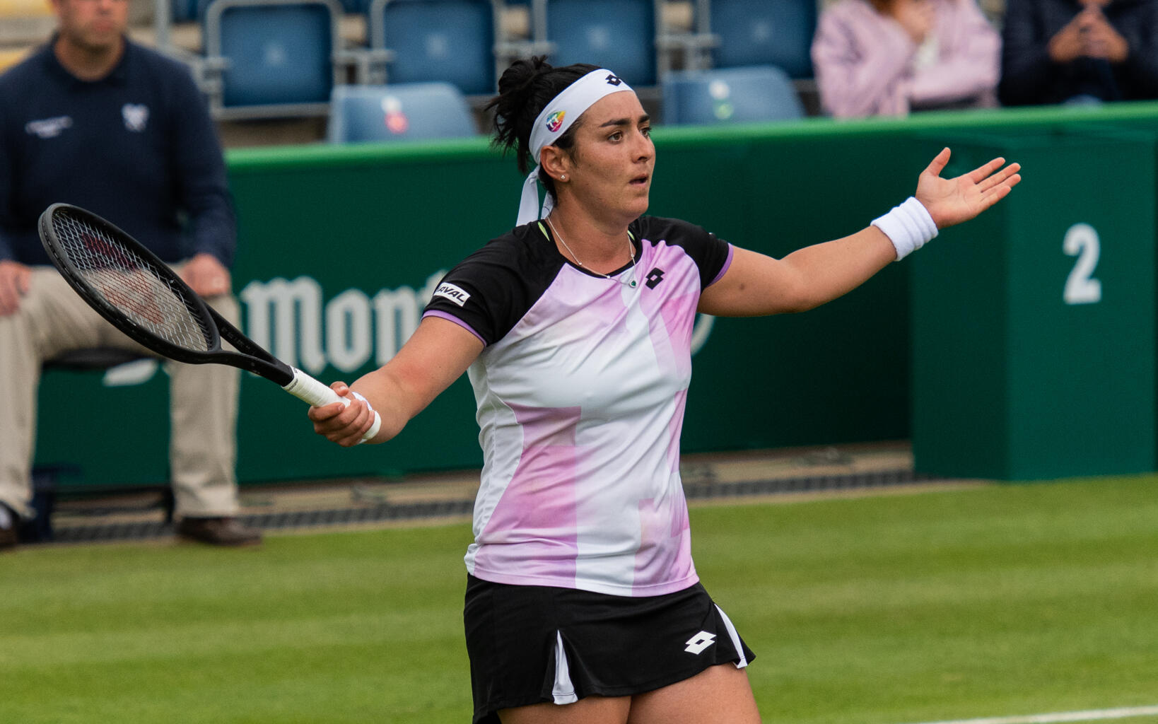 Ons Jabeur på planen. Hon höjer armarna och tittar ut ur bild.