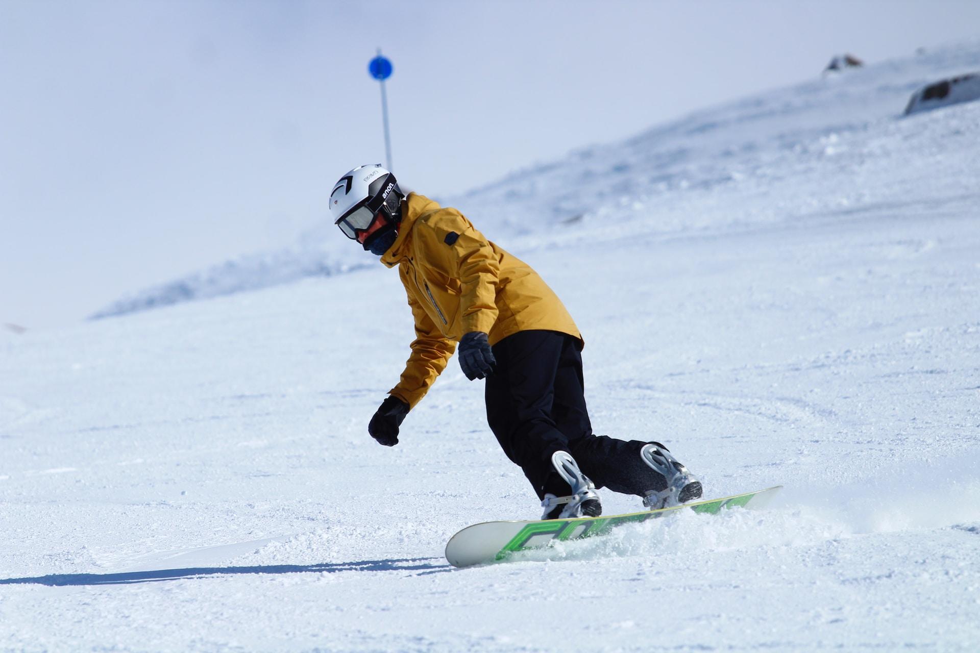 En snowboard-åkare på väg nedför i backen.