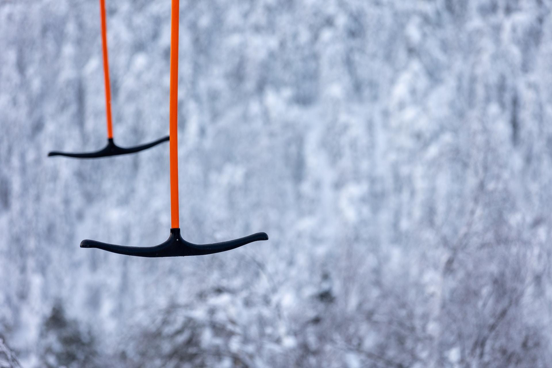 Två stycken ankarliftar syns i luften framför snötäckta träd.