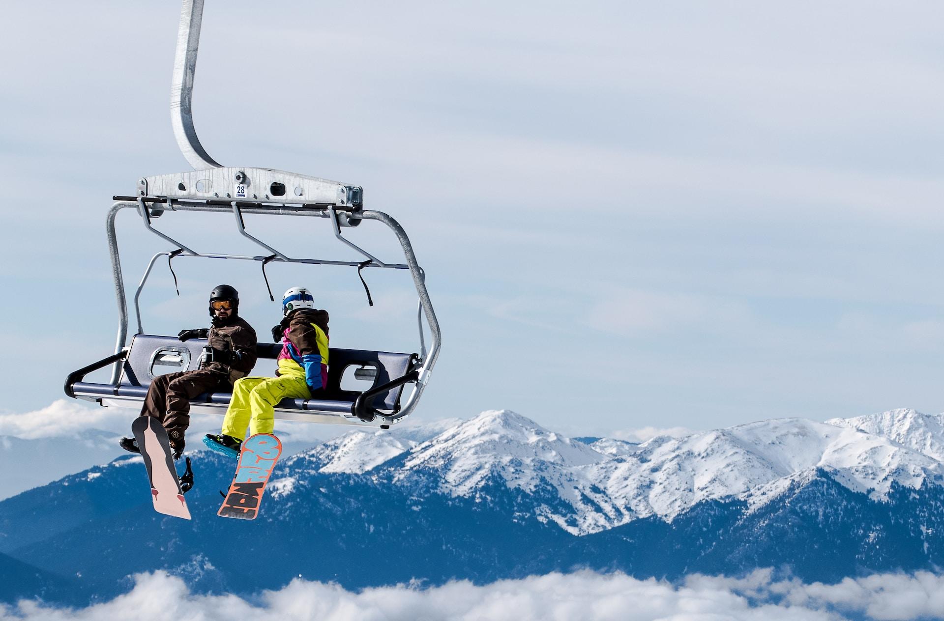 Två personer med snowboard i en stollift.