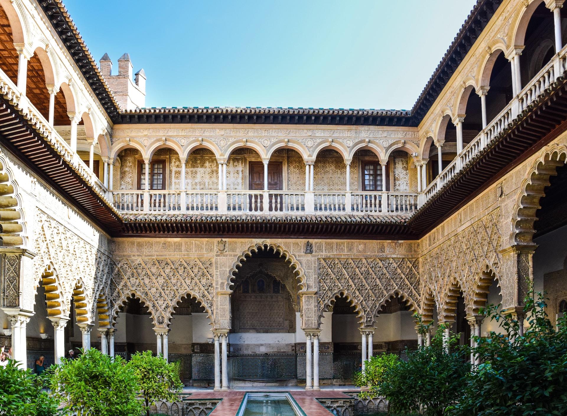 En stor byggnad med en innergård med Alcazar i Sevilla i bakgrunden