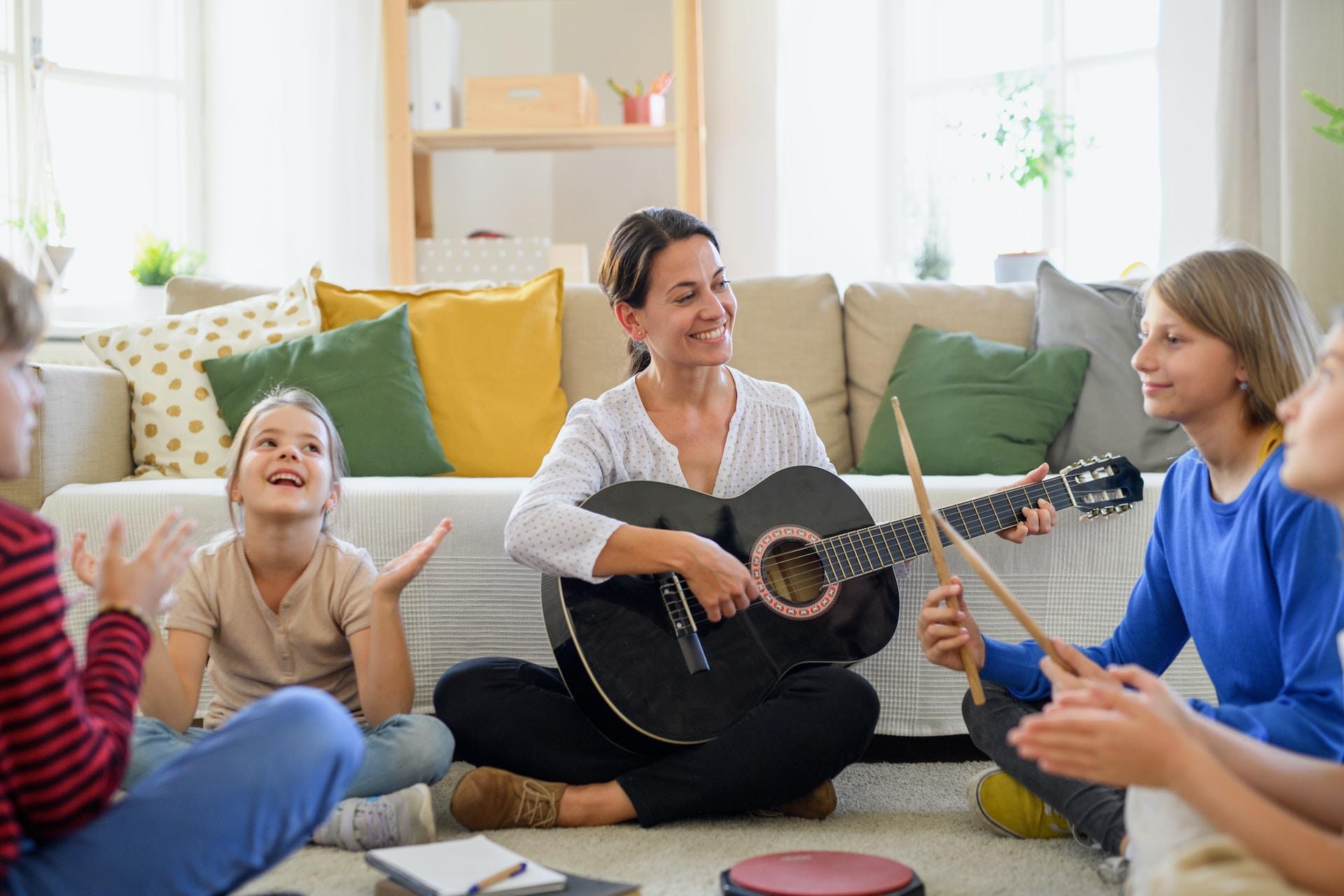 Barn som sjunger i grupp ledda av en vuxen med gitarr.