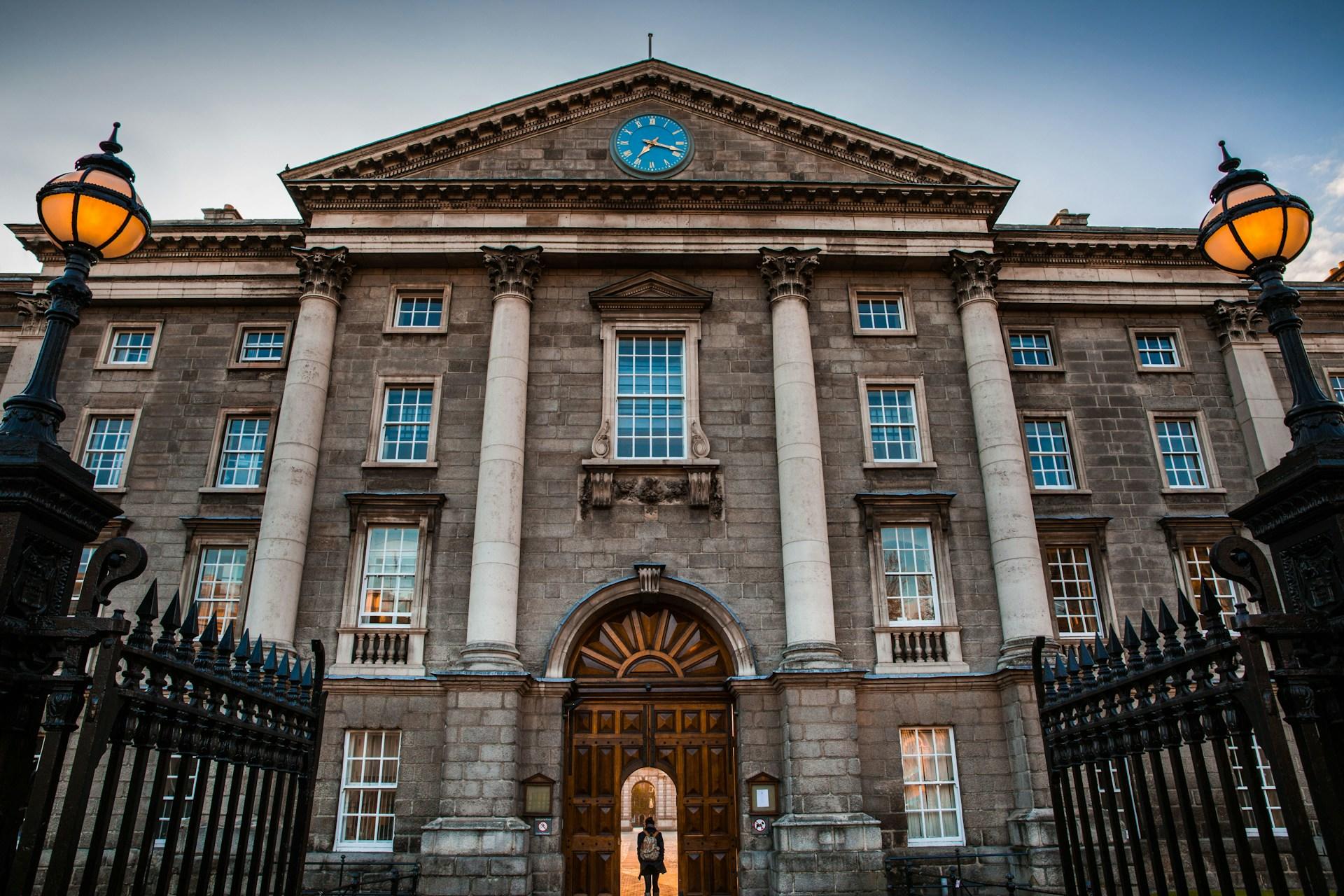 Utsida av Trinity college med student som står i dörren med ryggsäck