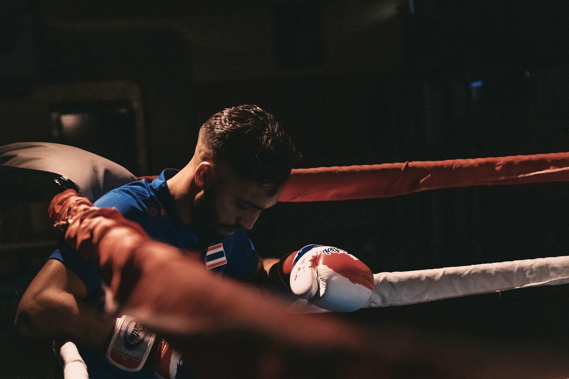 Boxare som sitter emot rep i boxningsring