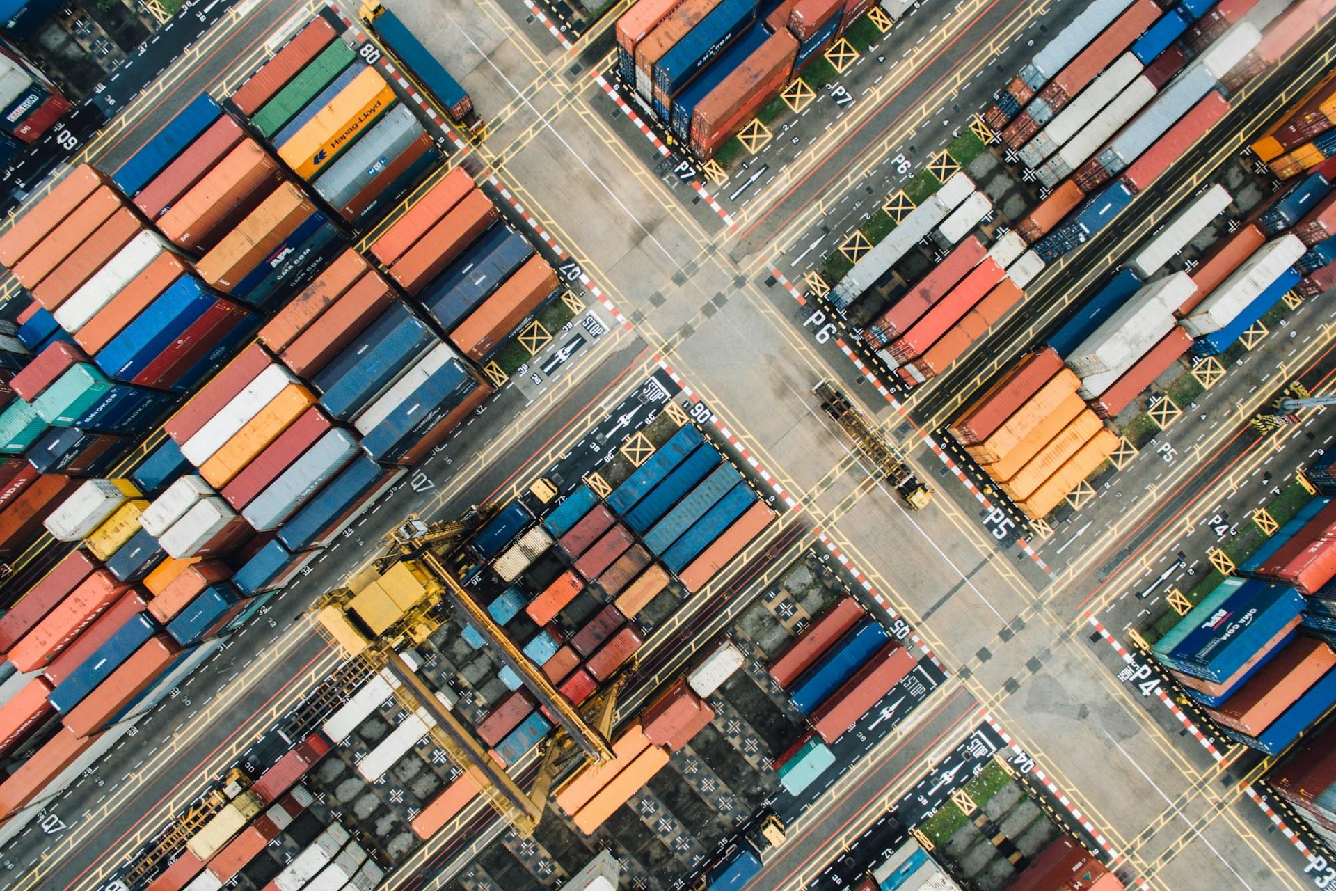 Flygfoto över hamnområde med containrar.