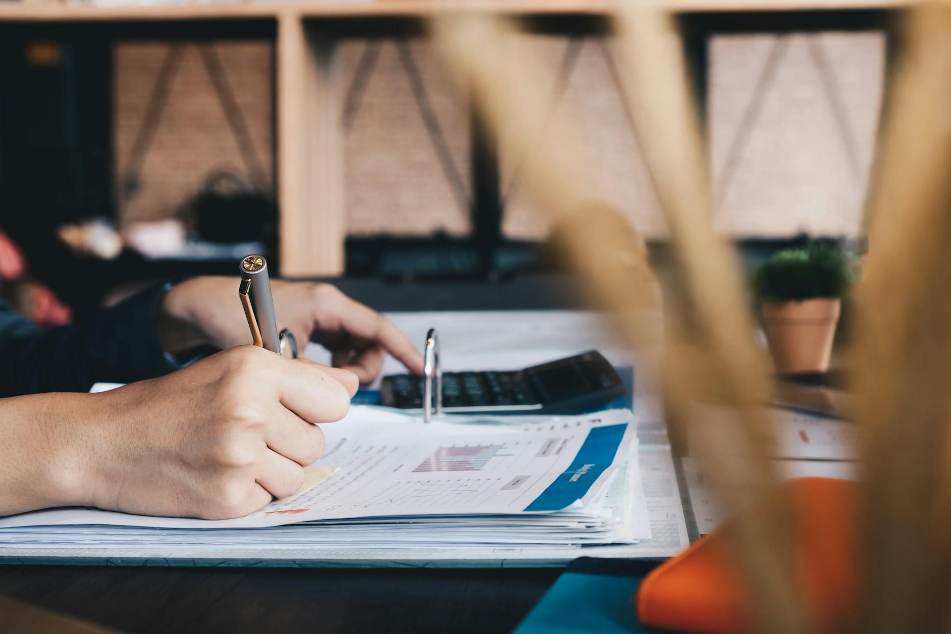 En person sitter och räknar matematik med uppslagen bok.