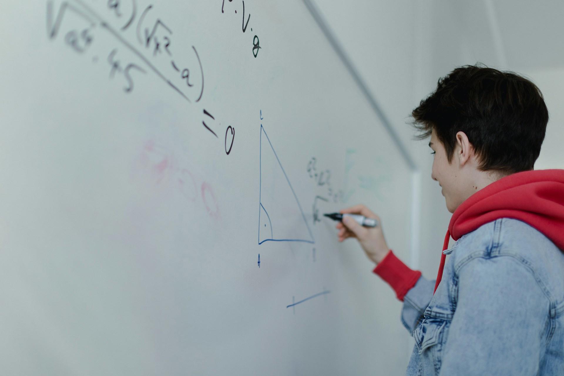 Elev räknar algebra på tavlan i ett klassrum.