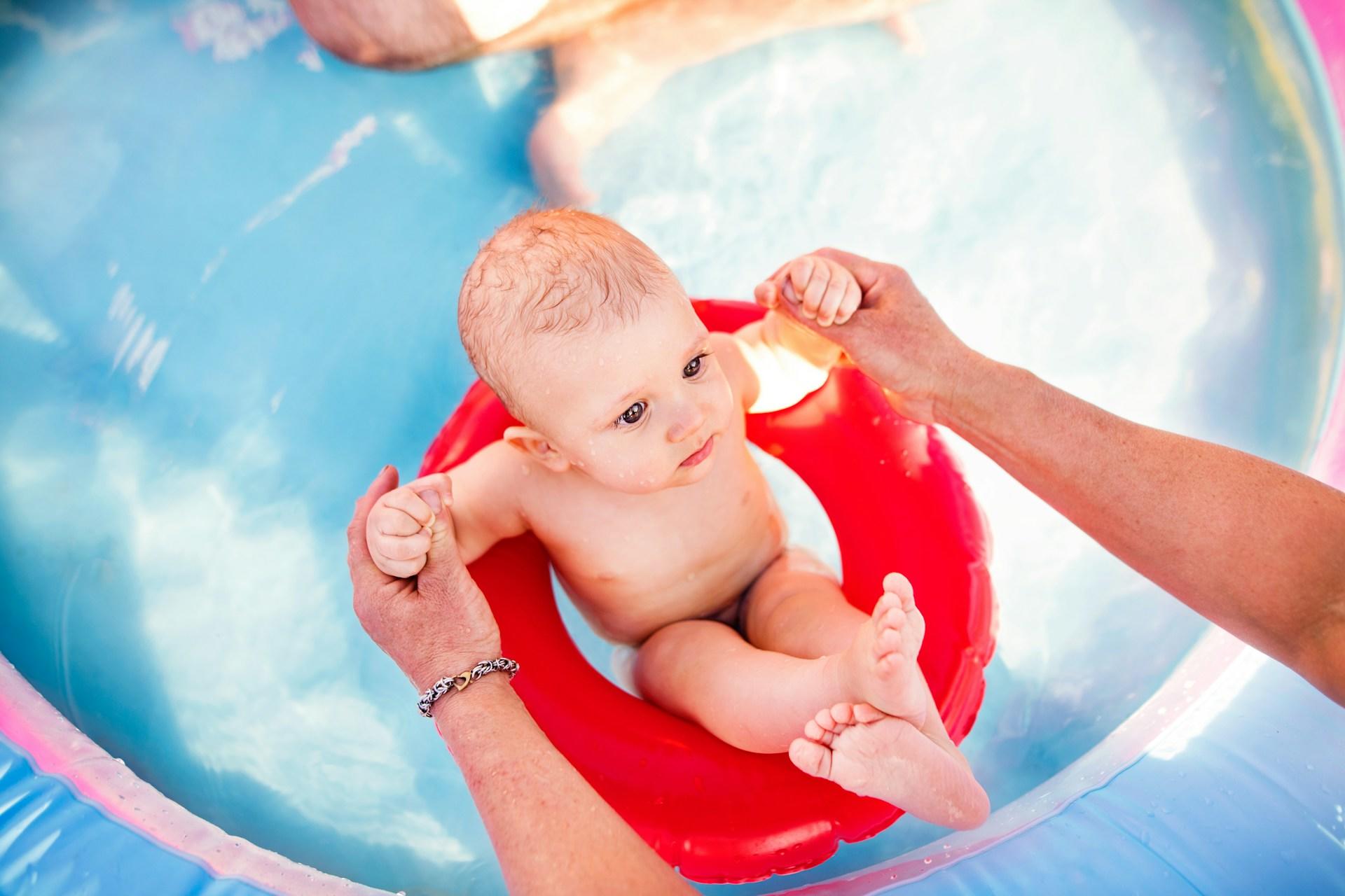 bebis med röd badring i pool