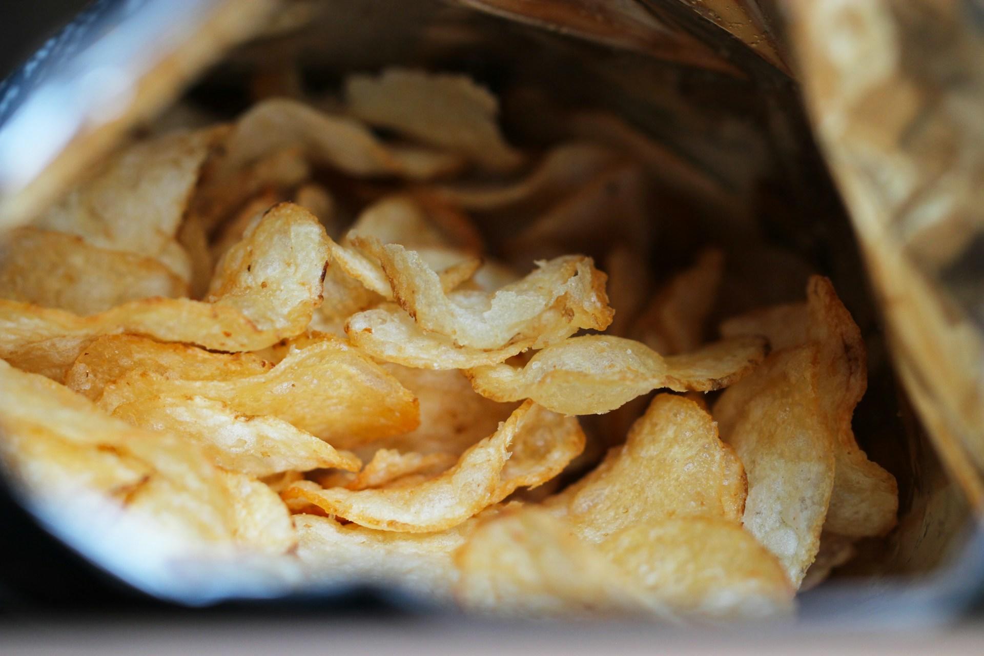 En öppnad chipspåse med chips i.