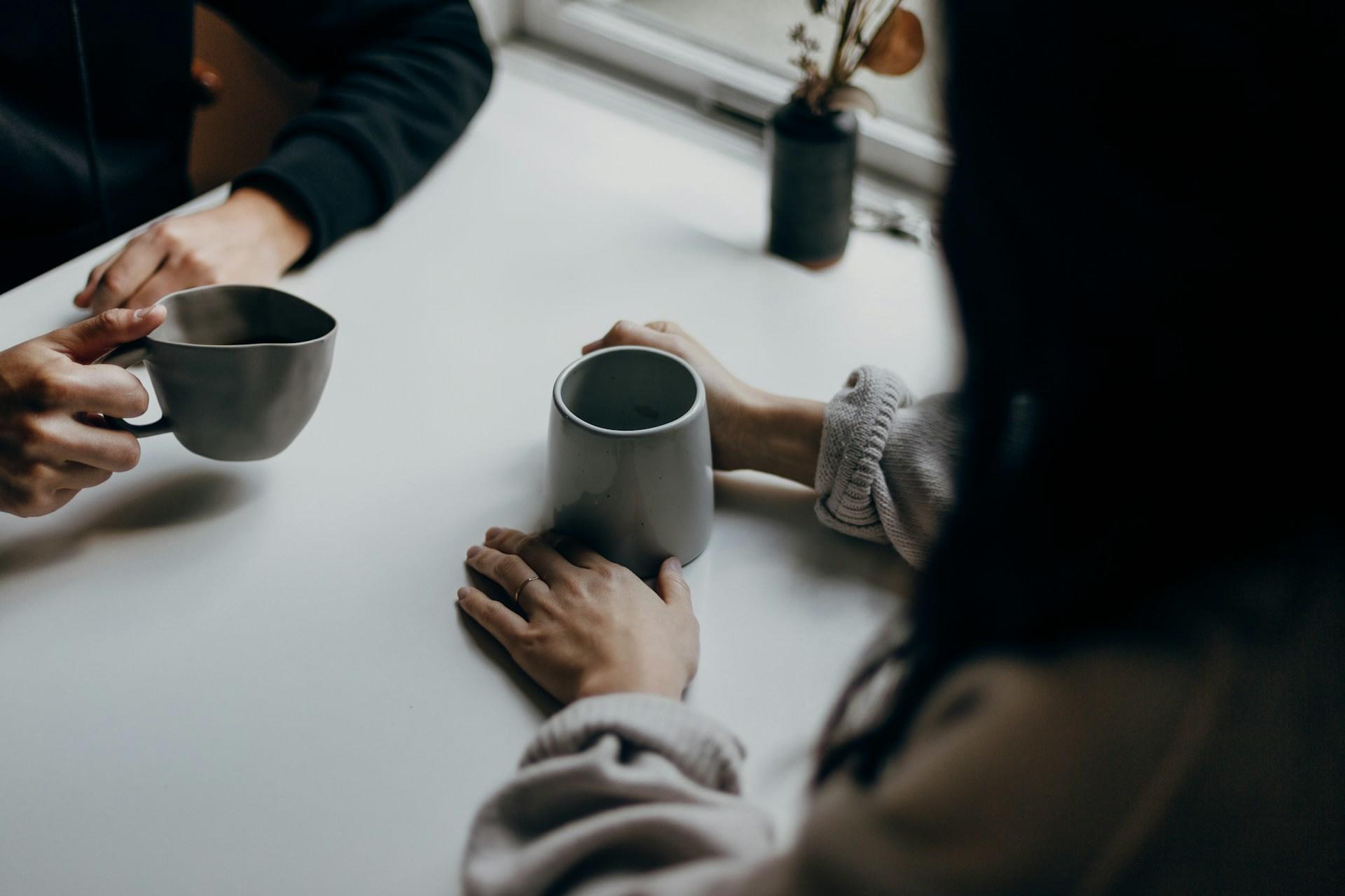 Två personer sitter mittemot varandra och dricker kaffe.