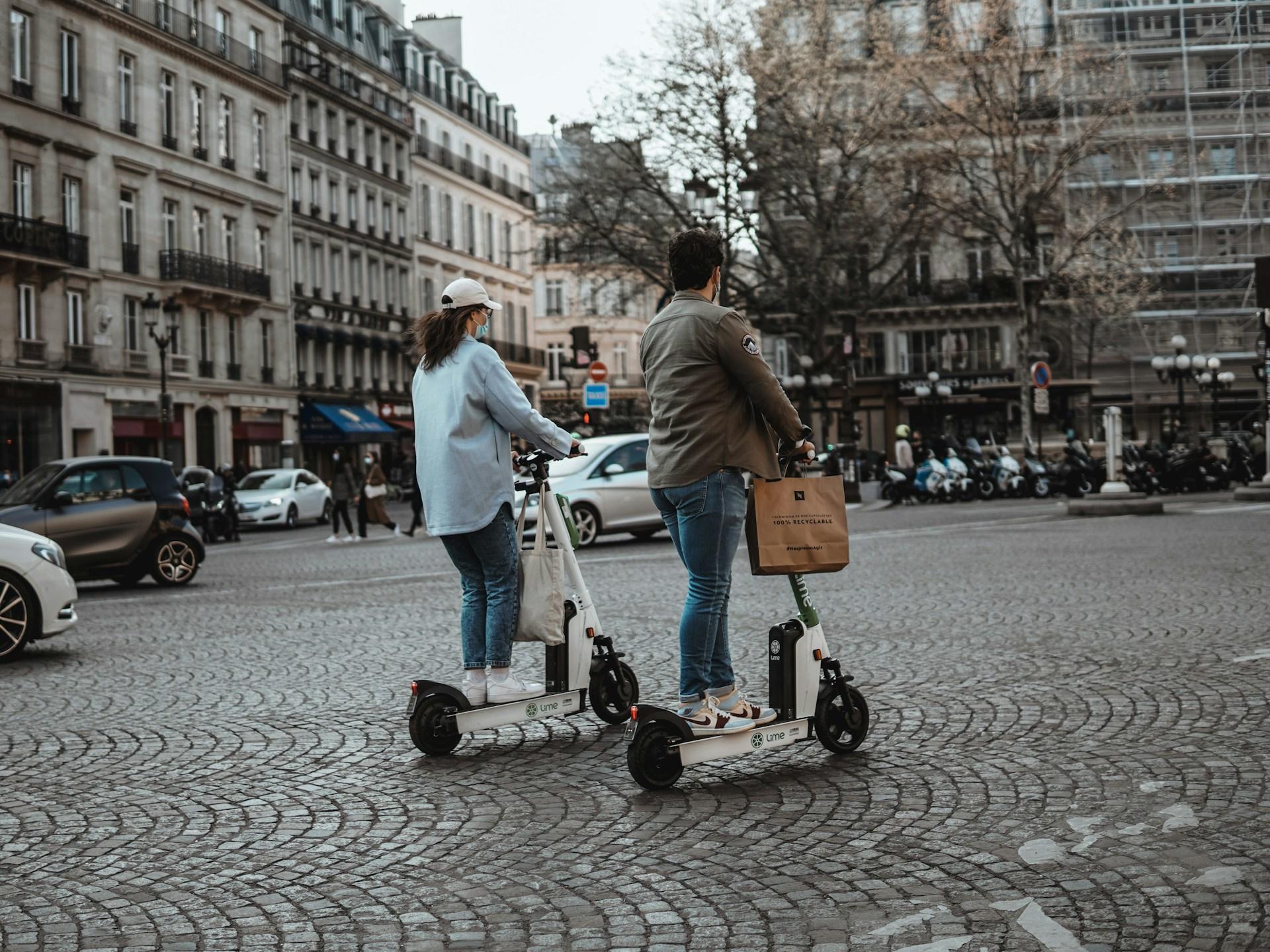 Två personer på varsin elcykel kör i trafiken.