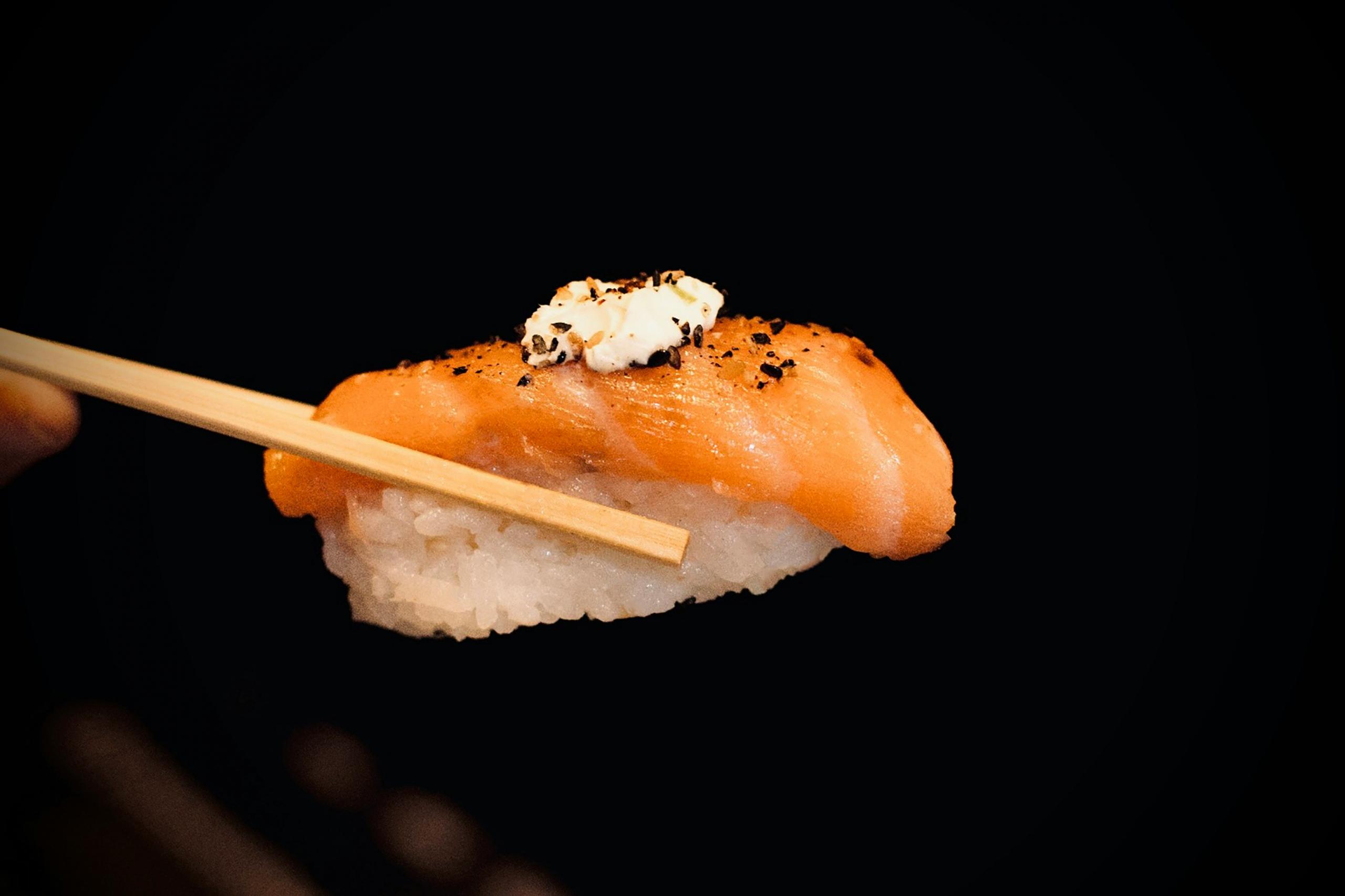 Nigiri som hålls med ätpinnar, trots traditionen