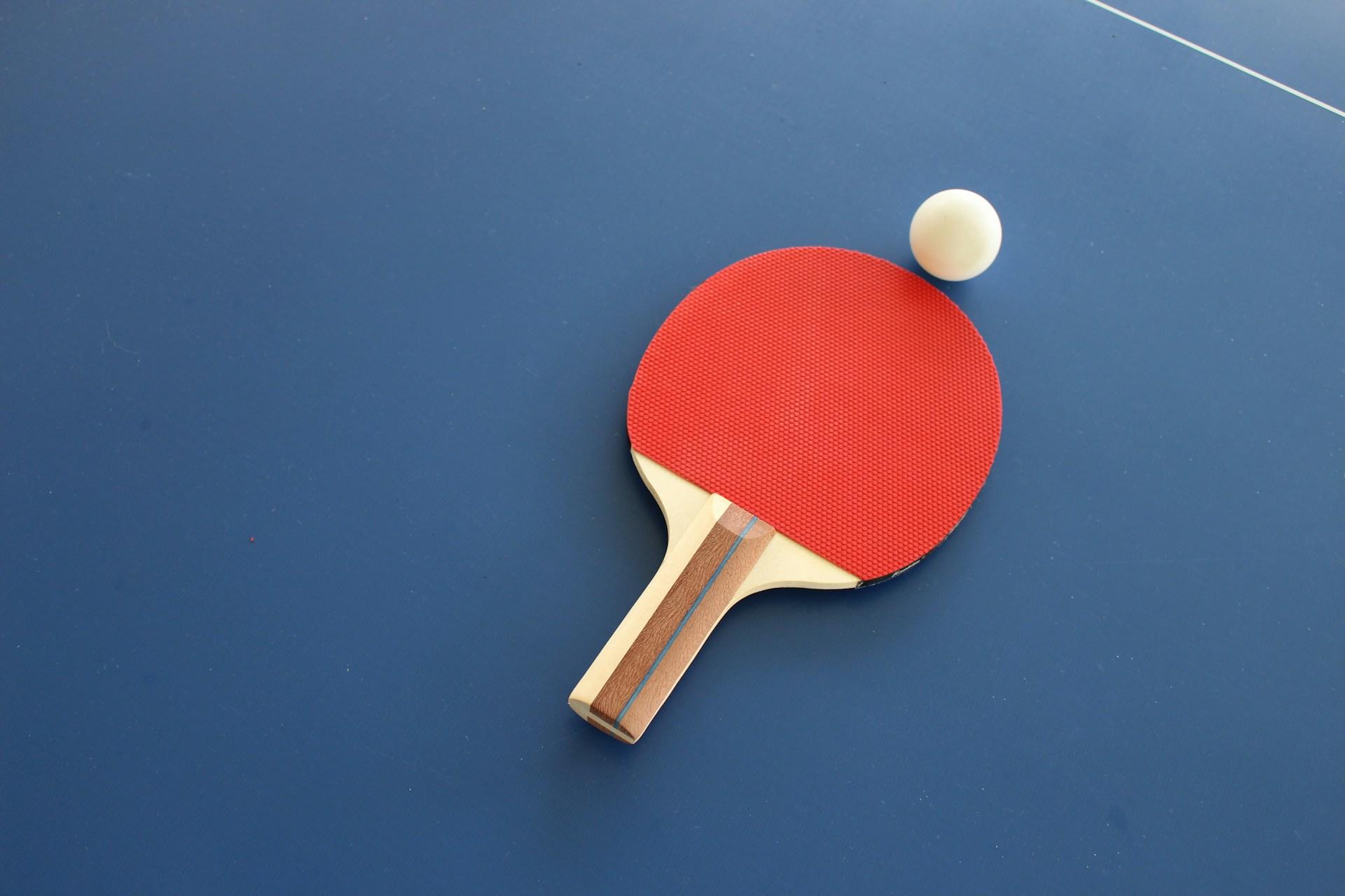 ett rött bordtennisracket på ett blått pingisbord