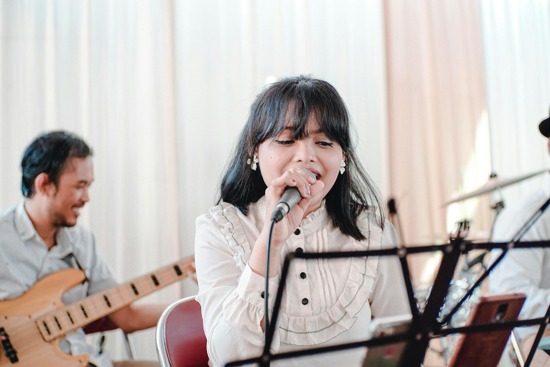 Kvinna som sjunger med mikrofon i handen ackompanjerad av en gitarrist.