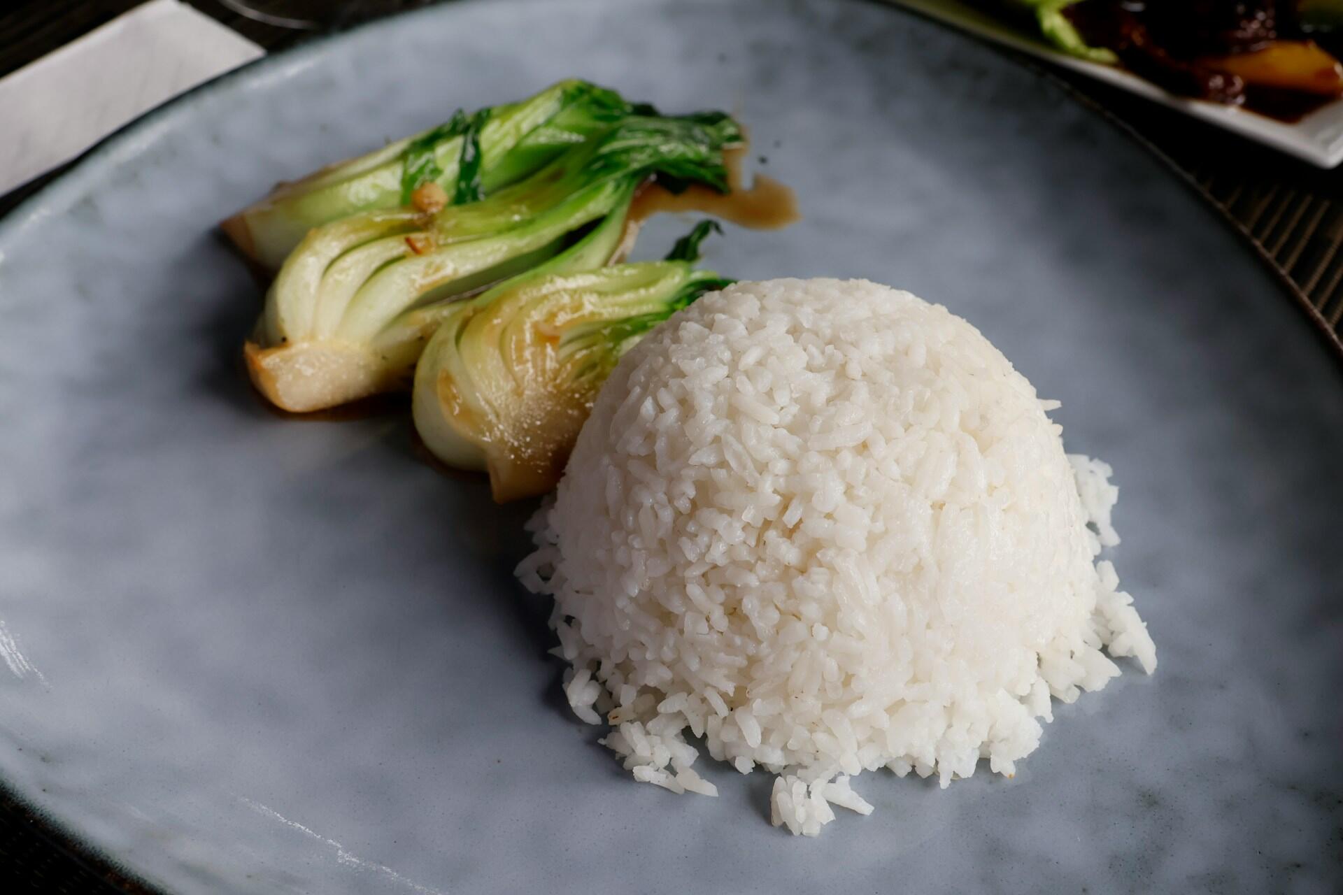 Närbild på en tallrik med ris och stekt pak choi. Kinesisk kål.