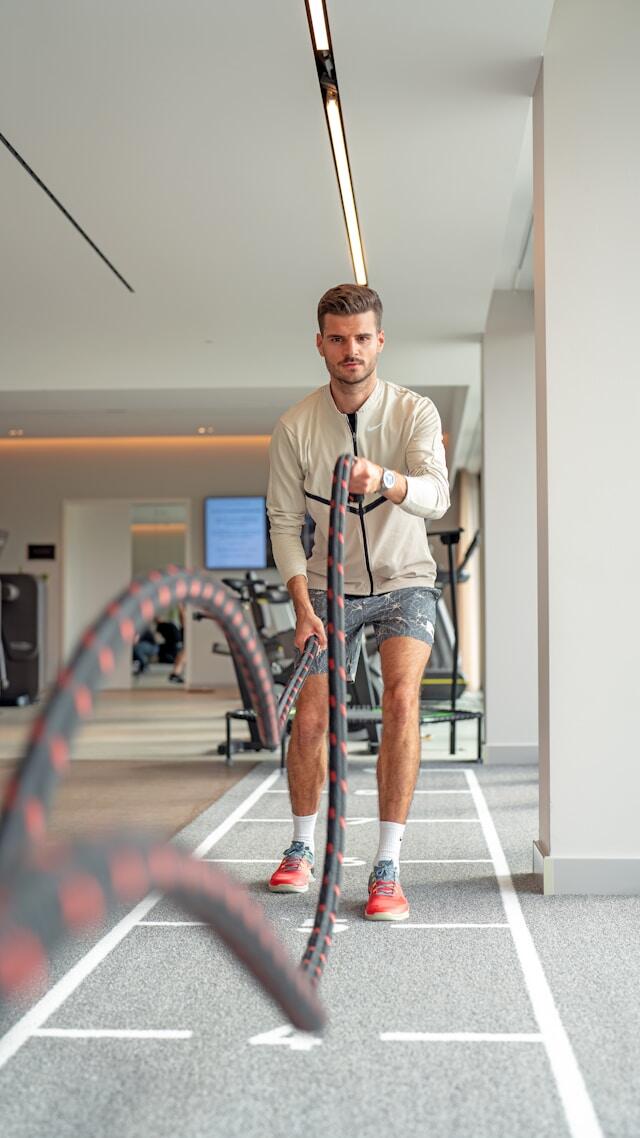 Man som tränar styrka med rep på ett gym.