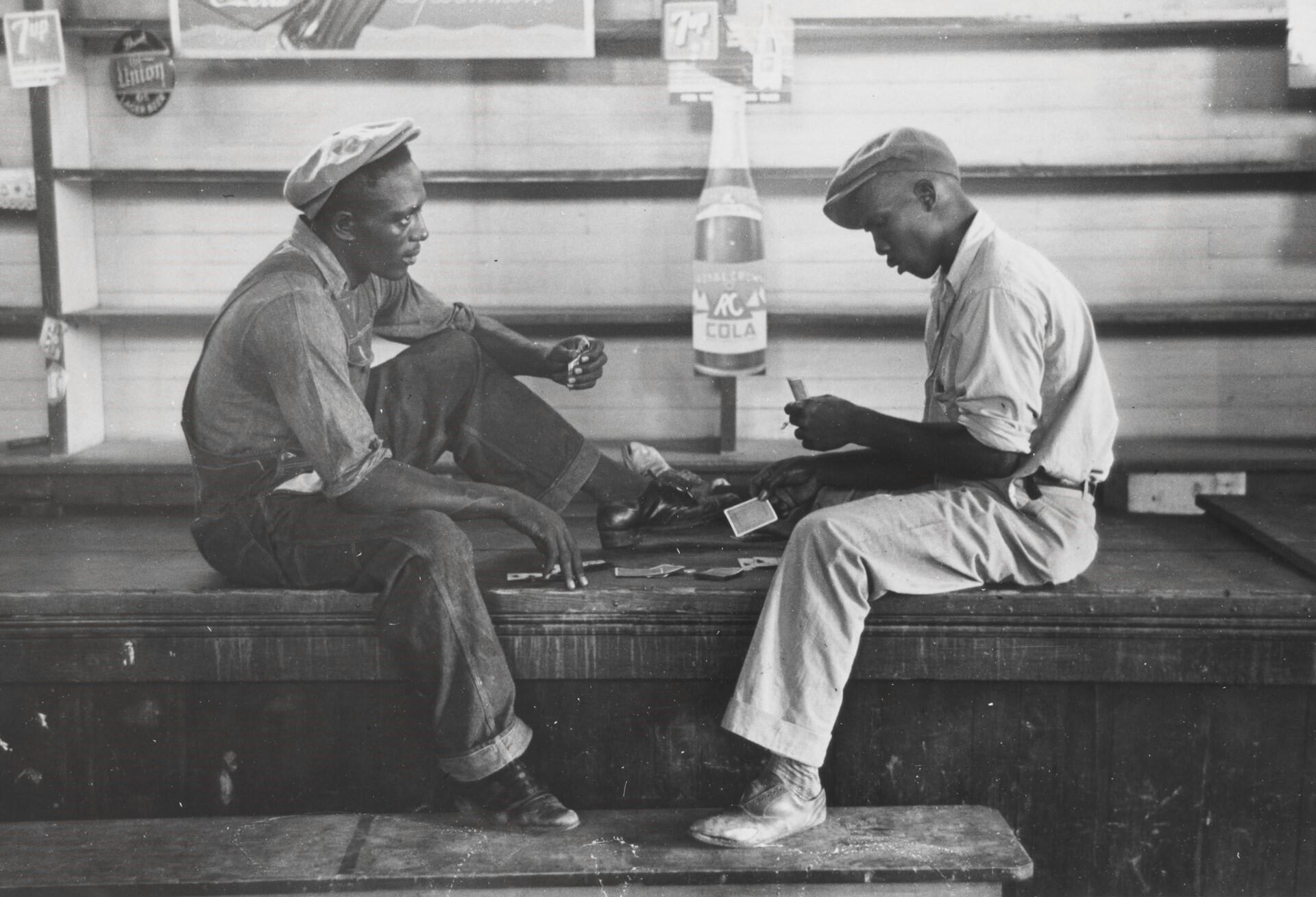 Två män sitter och spelar kort i en bar på 1930-talet.