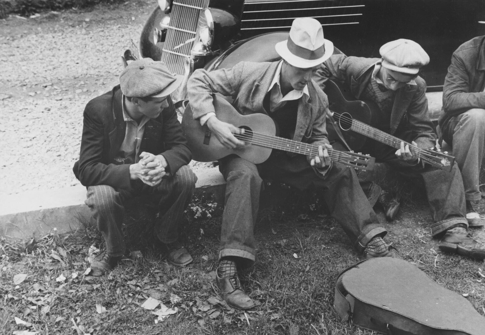 Tre musiker som sitter på marken och spelar.