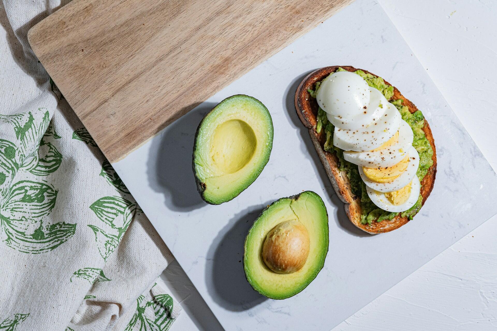Mökare bröd och ägg och avocado på ett bord 