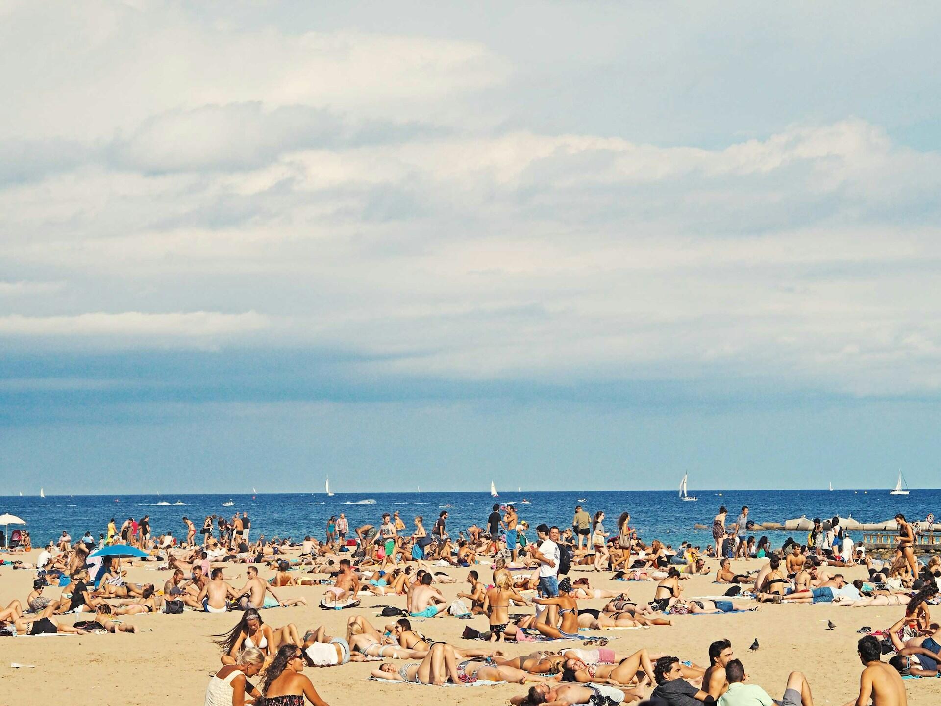 Folk som solar och badar på en sandstrand.