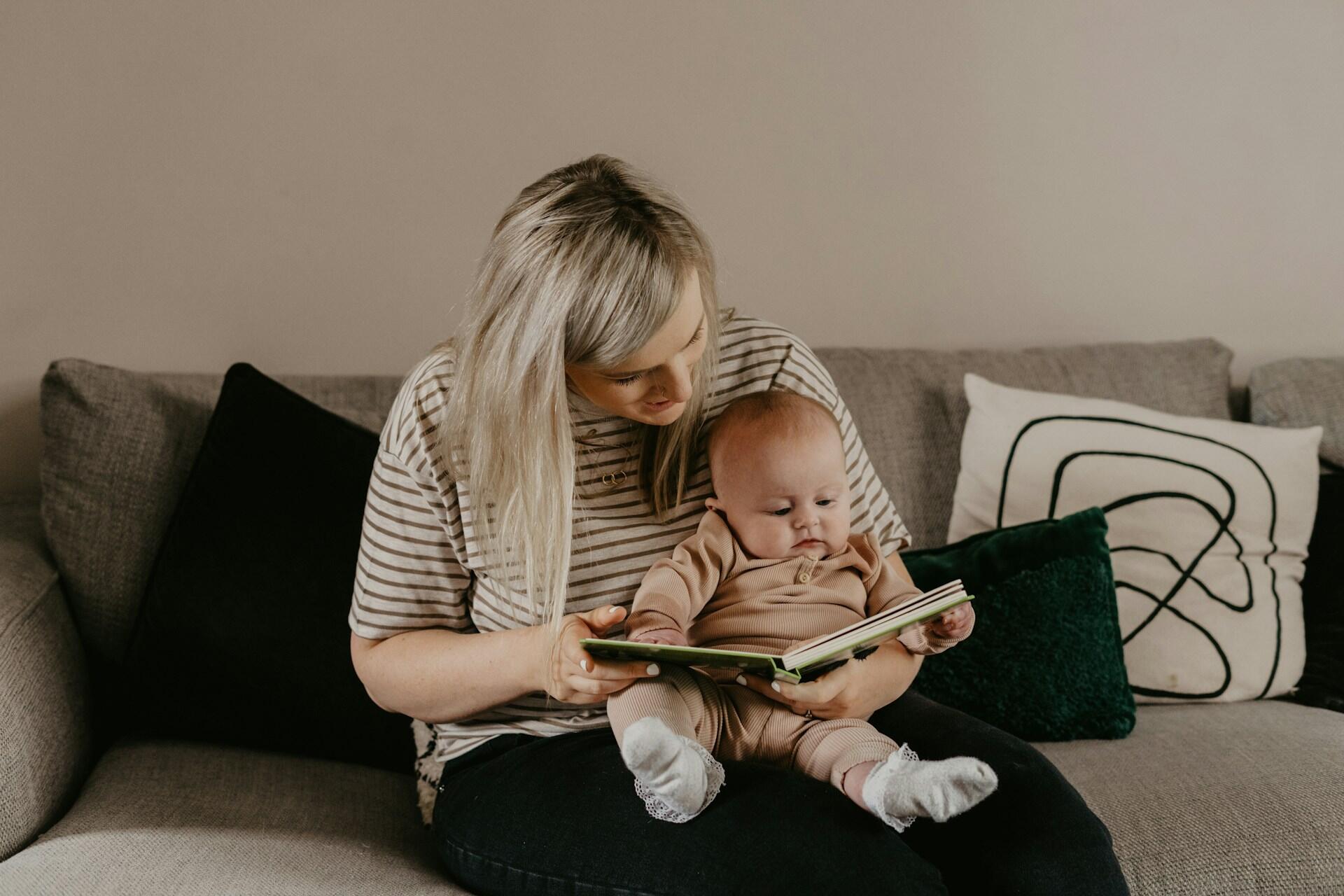 Mamma sitter och läser pekbok för sin bebis.