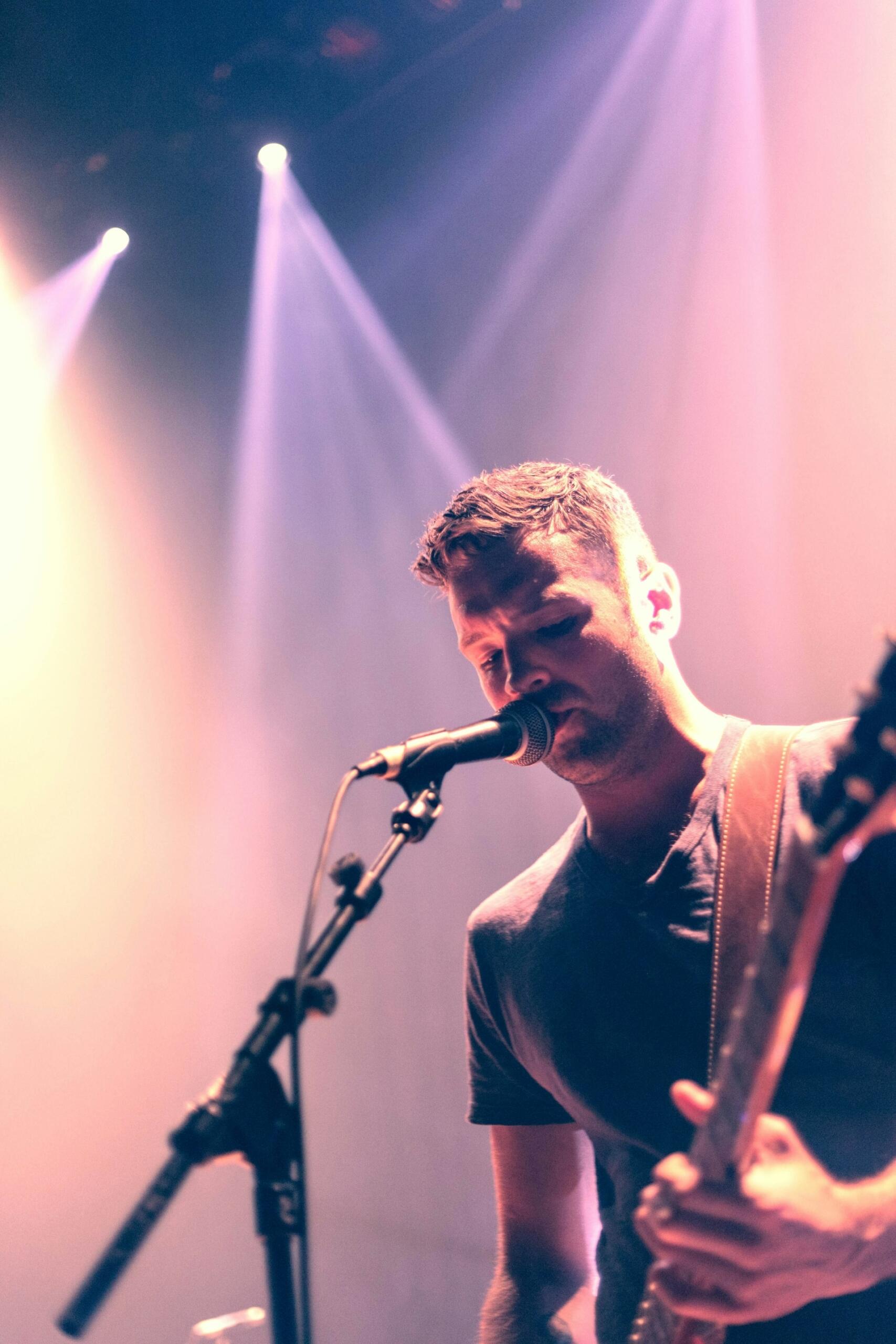 En sångare som står på scen med gitarr i händerna.