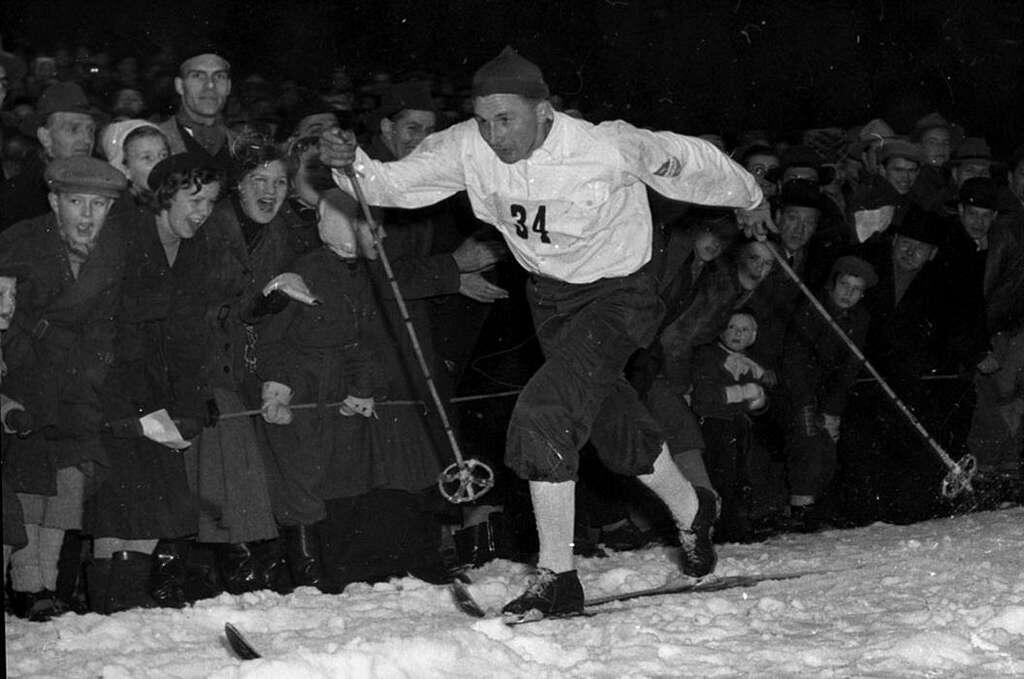 Skidåkaren Nils "Mora-Nisse" åker ett skidlopp i Stockholm 1951. Publik står och hejar på i bakgrunden.