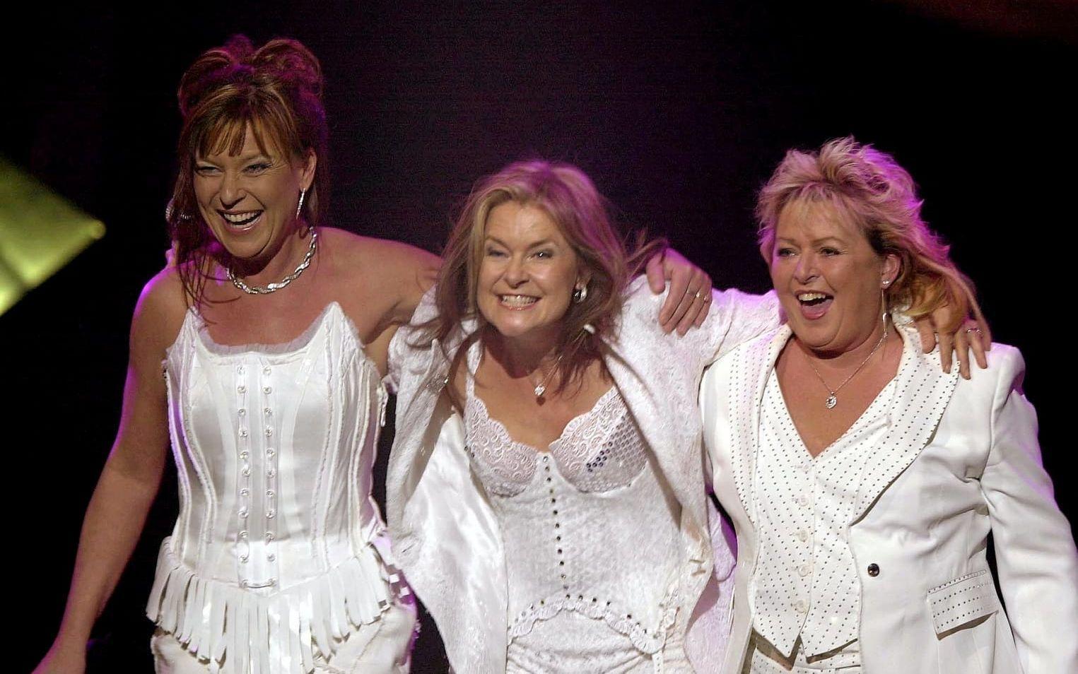 Kicki, Bettan och Lotta på turné. De tre kvinnorna, alla klädda i vitt står på scenen och ler mot publiken.