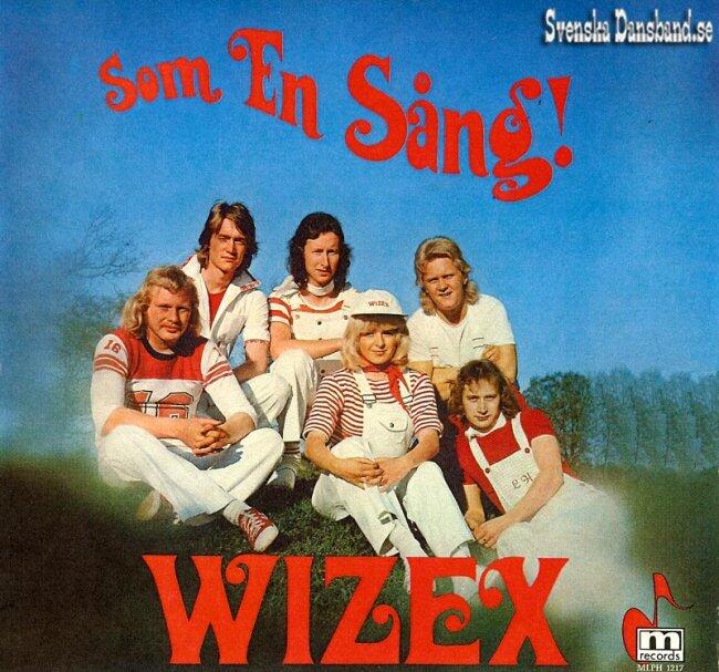 Albumomslag för ”Som En Sång!” av Wizex, med en grupp i vintage-kläder sittande på gräset, med en blå himmel i bakgrunden.